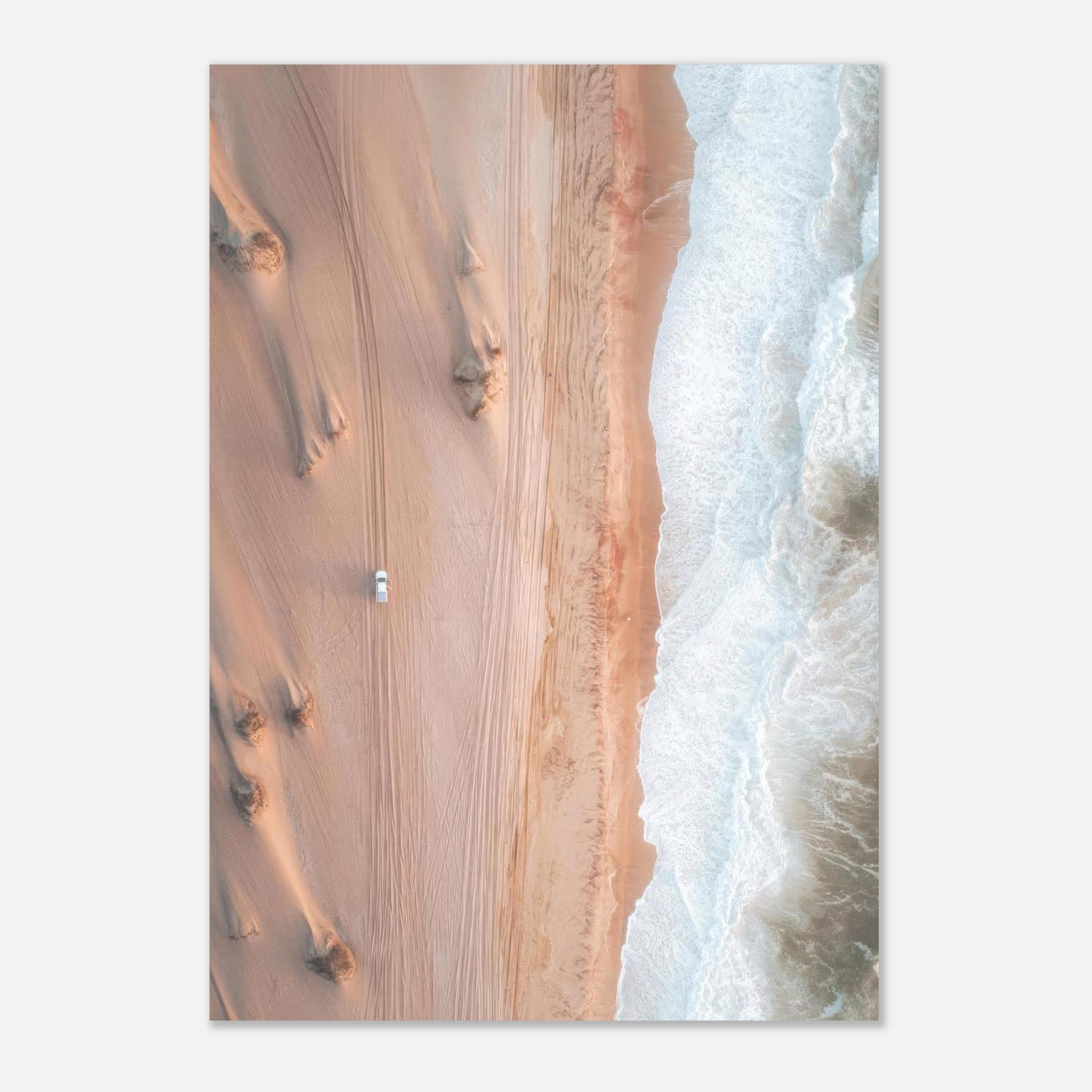 Aerial view of a coastline where golden sand dunes meet ocean waves, highlighting nature's beauty.
