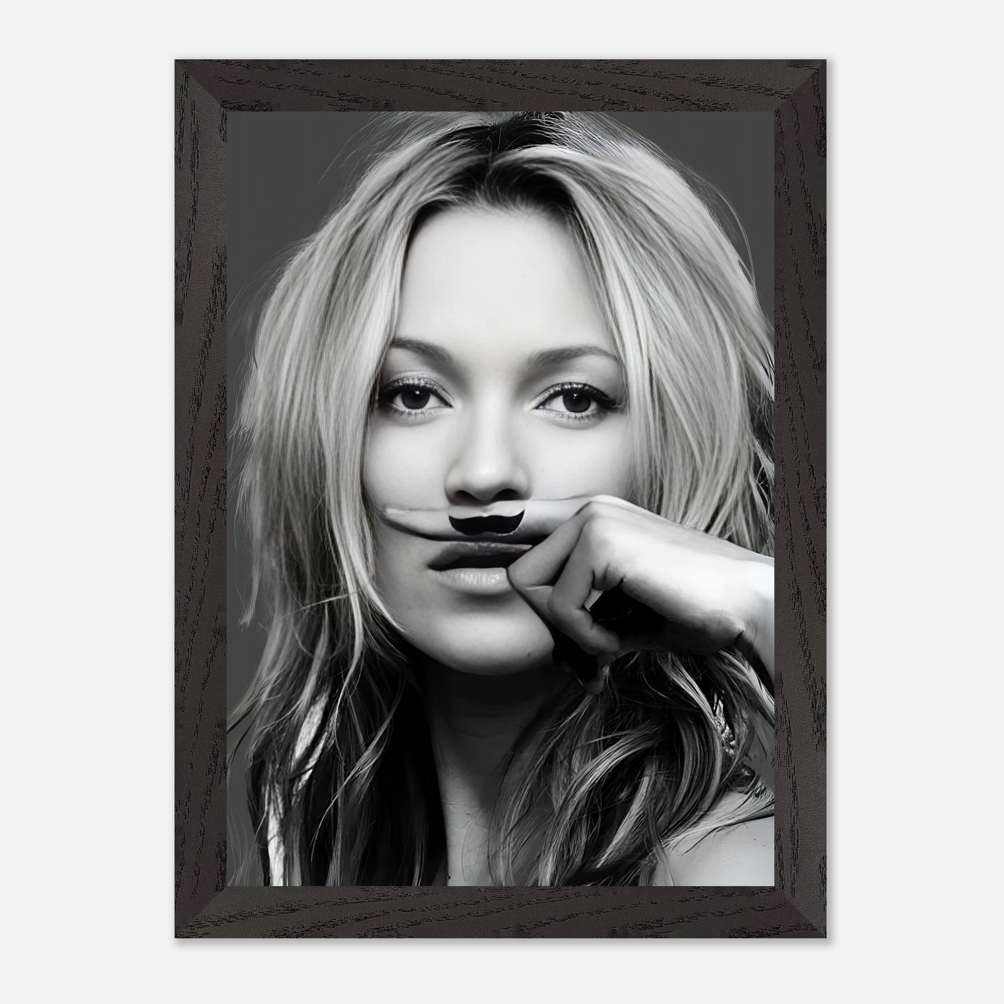 Vintage framed print of Kate Moss holding a playful mustache, blending high fashion with humor in black and white.