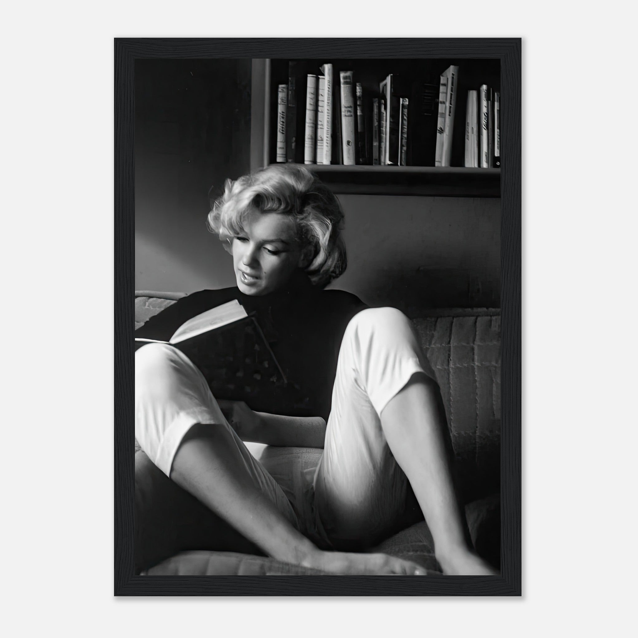Marilyn Monroe reading a book at home, captured in a timeless black-and-white framed print.