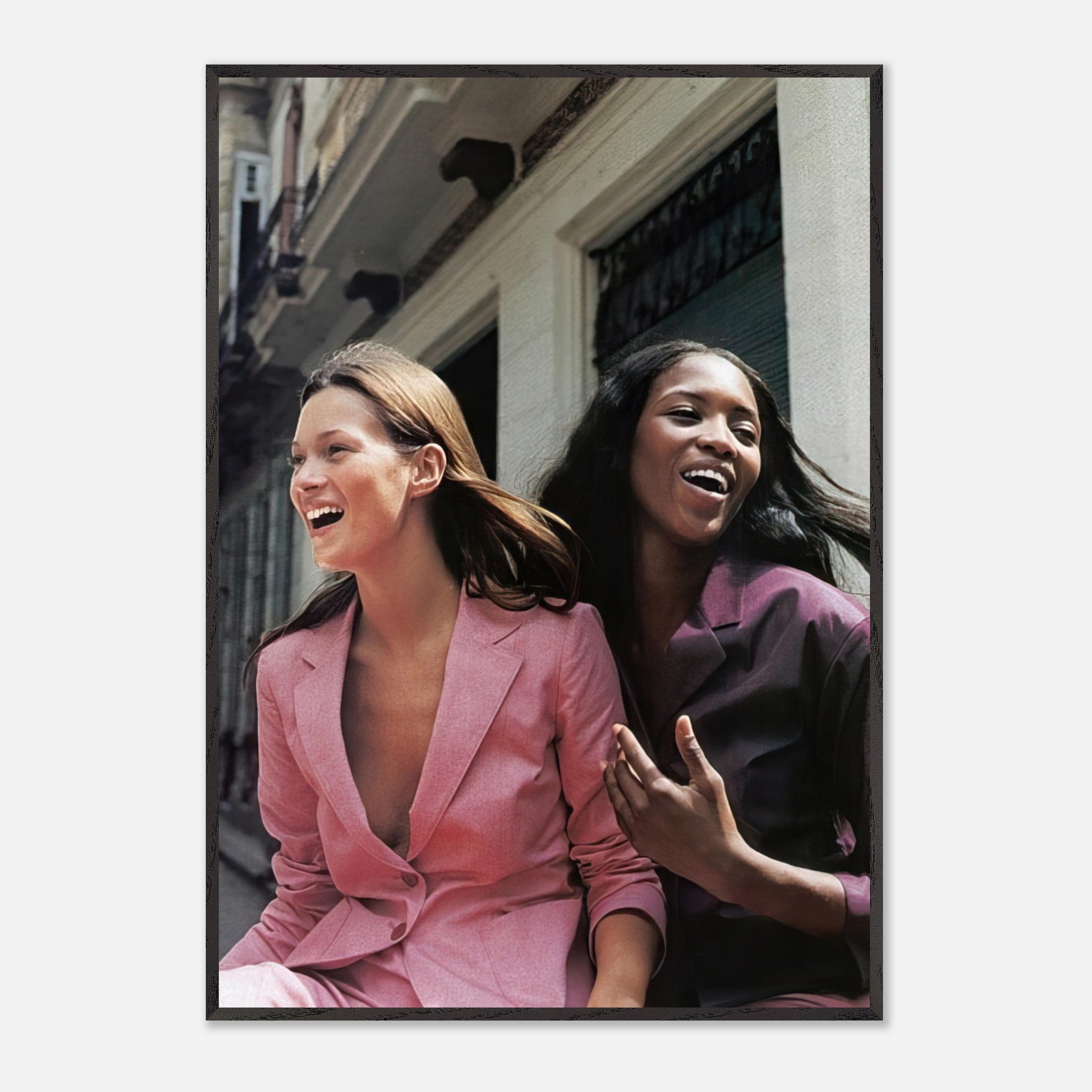Naomi Campbell and Kate Moss laughing together in stylish outfits, capturing the essence of high fashion and friendship.
