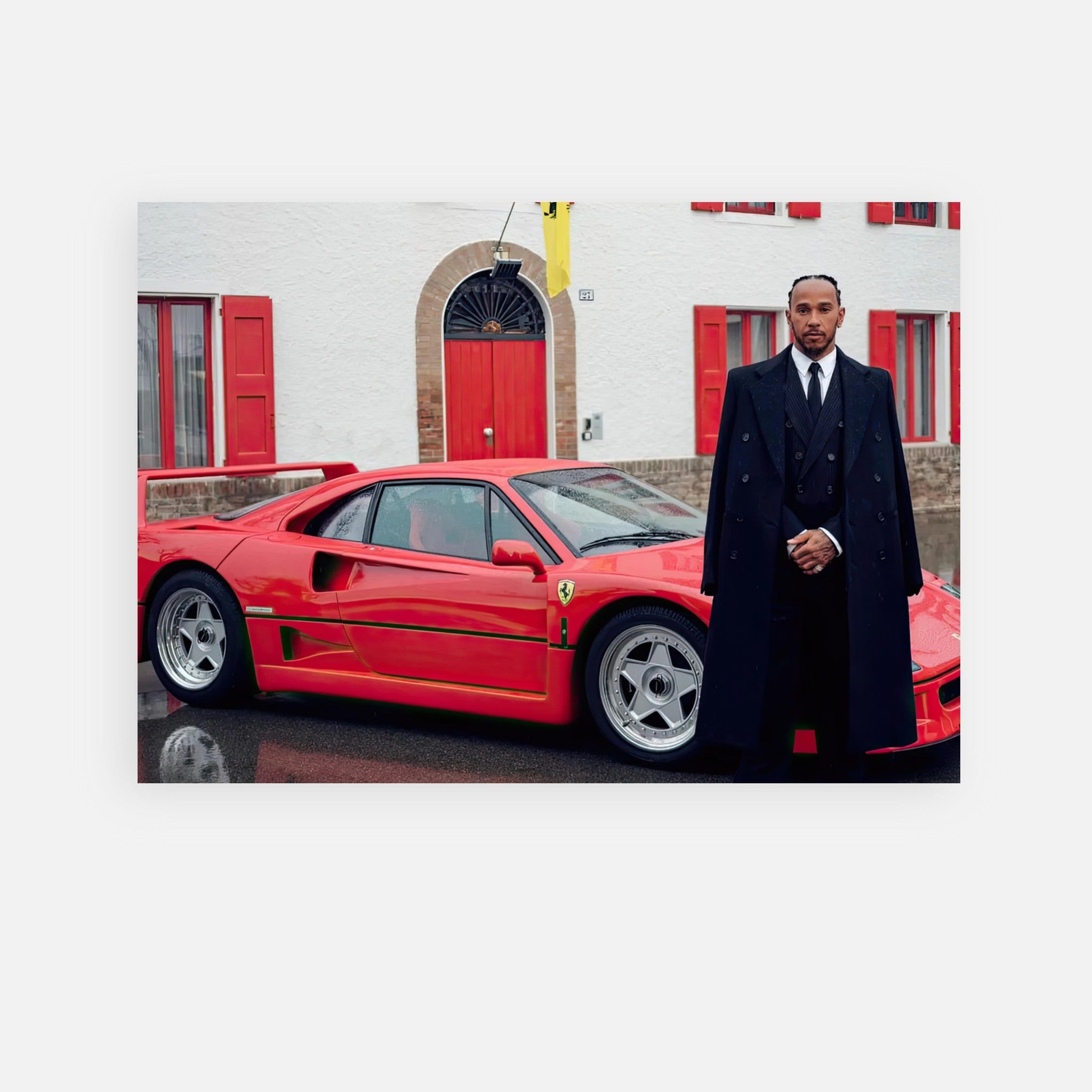 Lewis Hamilton posing in a stylish coat beside the iconic Ferrari F40 in front of Enzo Ferrari's home.