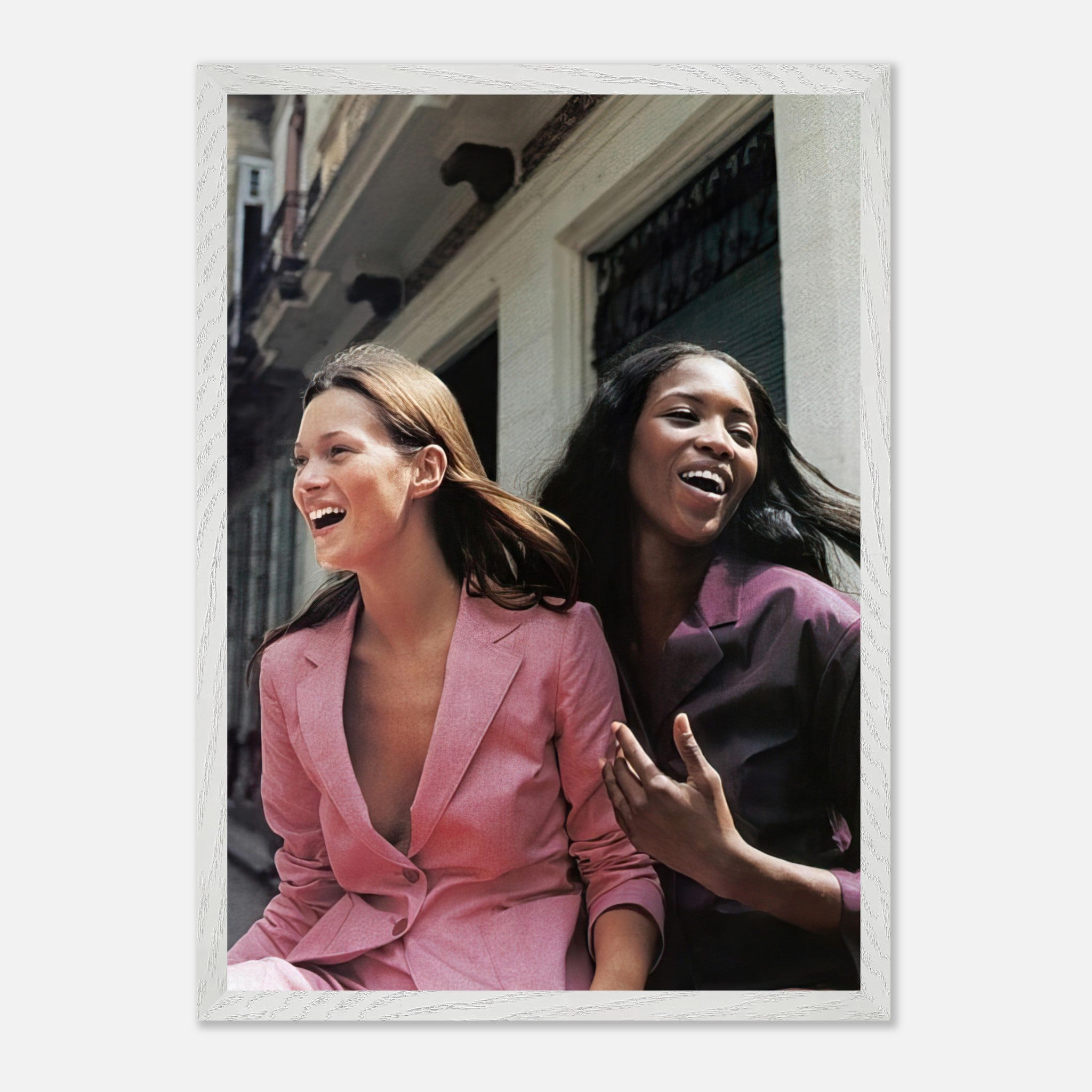 Naomi Campbell and Kate Moss laughing together in stylish blazers, celebrating friendship and fashion iconography.