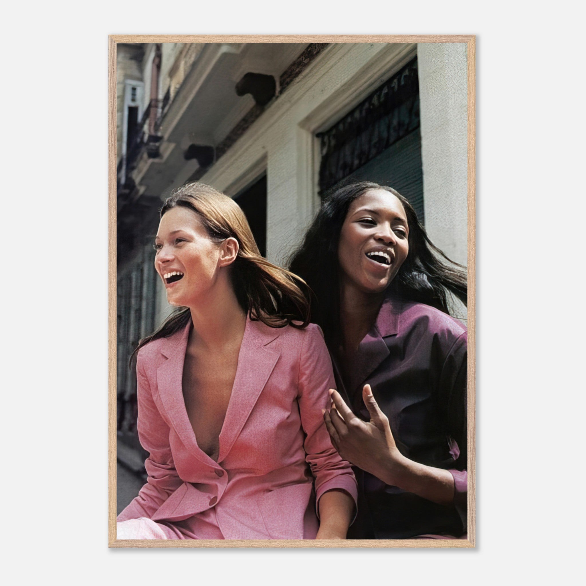 Naomi Campbell and Kate Moss laughing together in stylish outfits, showcasing friendship and timeless fashion elegance.