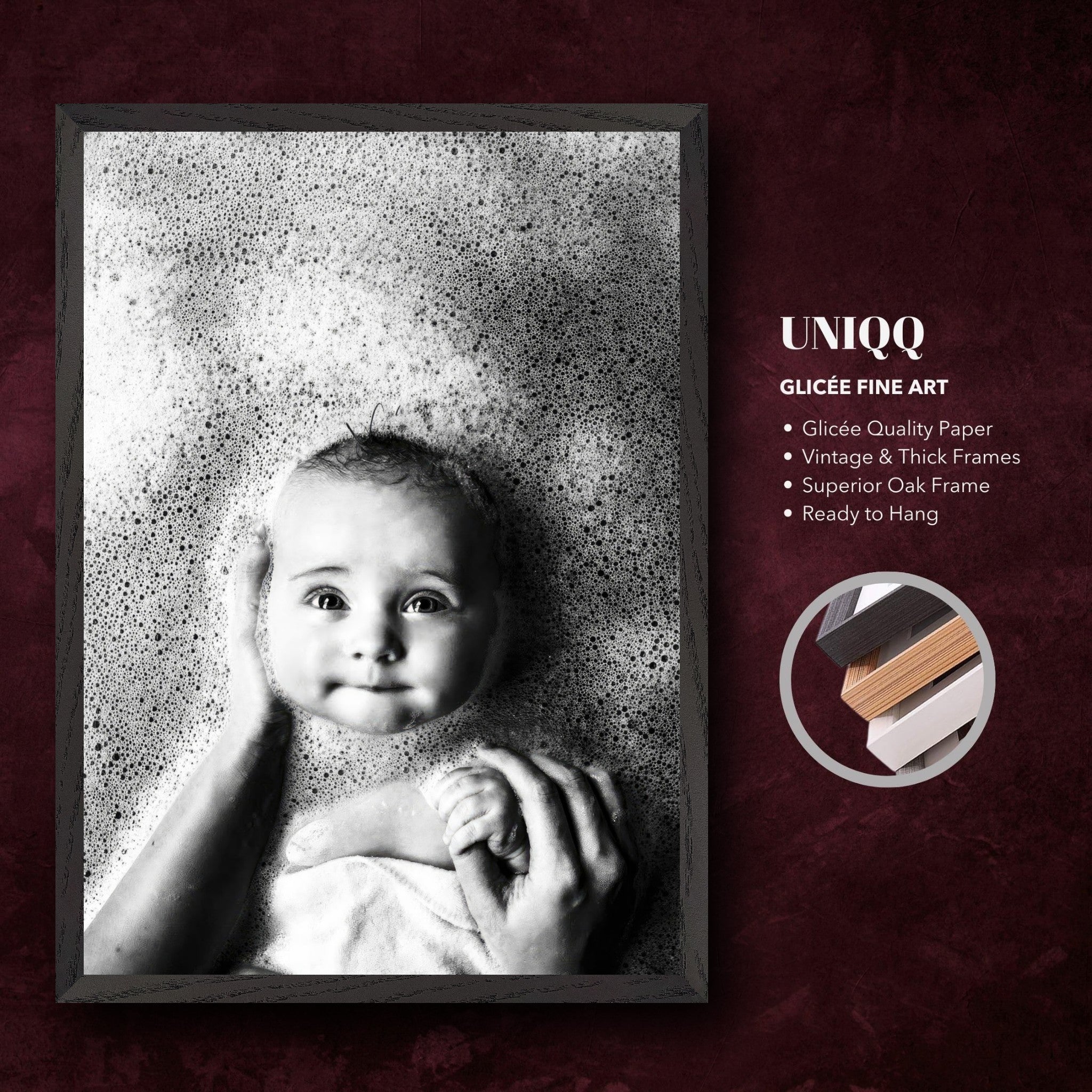 Black-and-white fine art print of a baby in a bath surrounded by bubbles, framed in vintage oak.