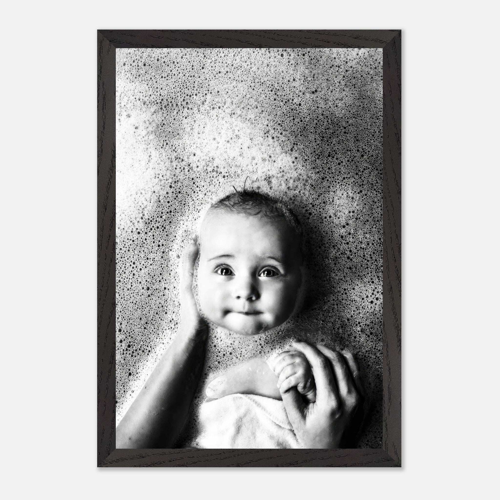 Black-and-white fine art photography of a smiling baby in a bubble bath, capturing innocence and joy.