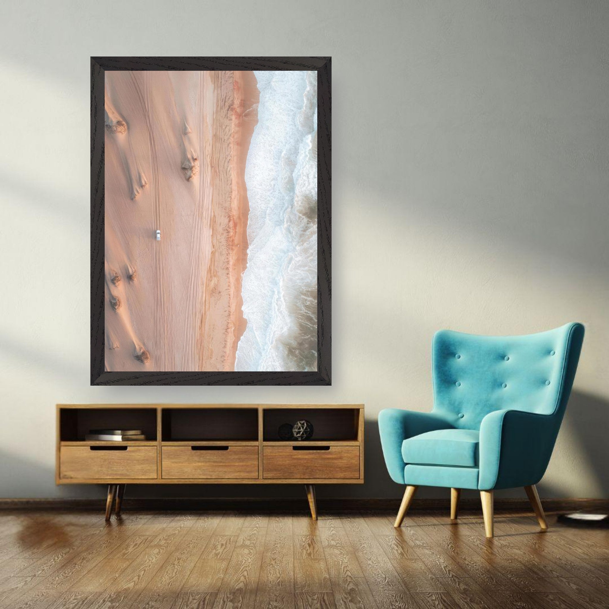 Vintage framed print of desert and ocean drone photography, featuring golden dunes and blue waves in a modern living space.