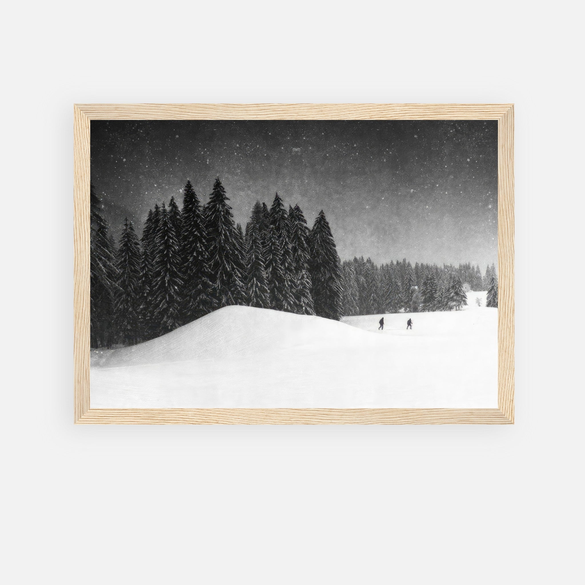 Black-and-white framed print of snow-covered landscape with evergreens and figures in the distance.