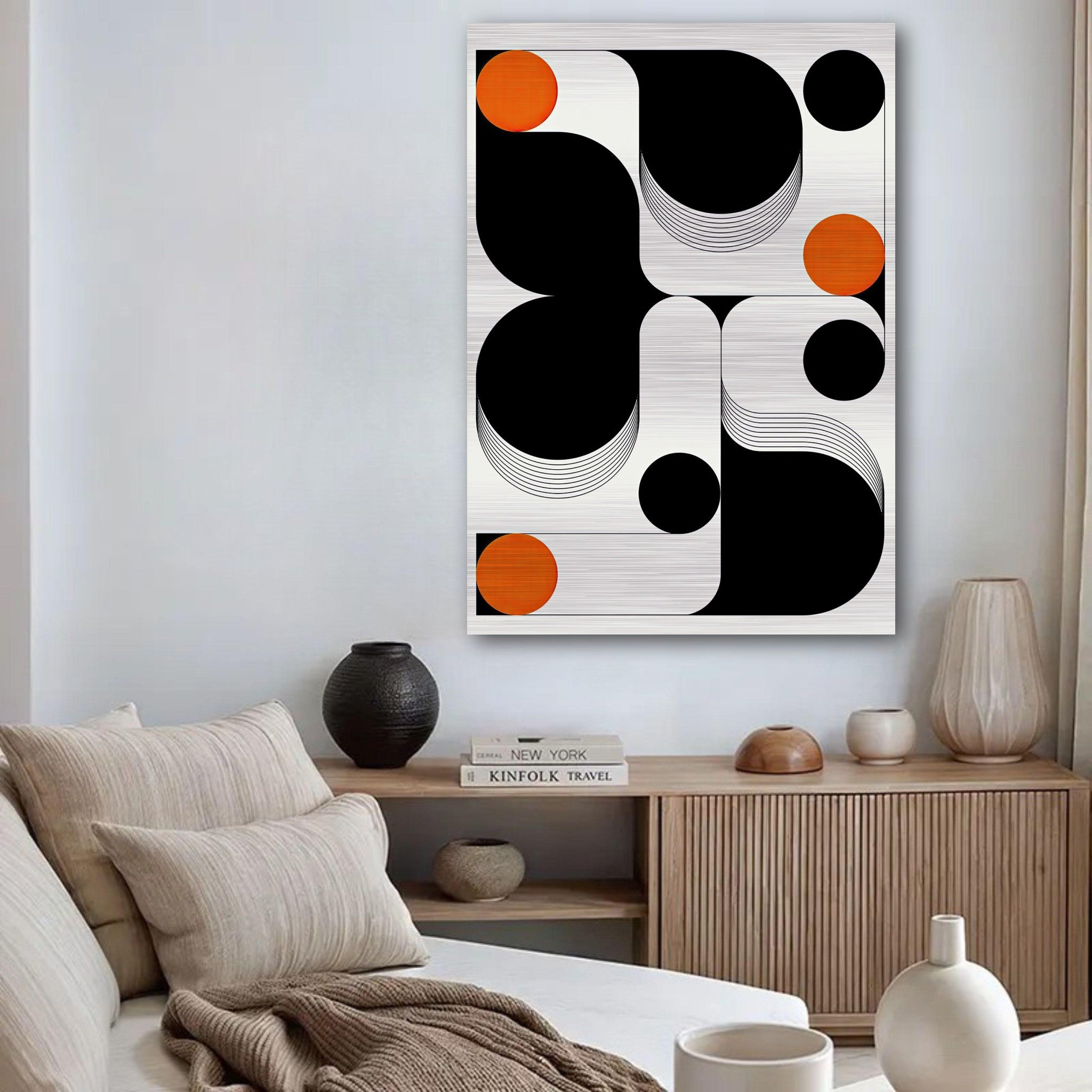 Modern geometric abstract art in black, white, and orange on brushed metal, displayed in a stylish living room.