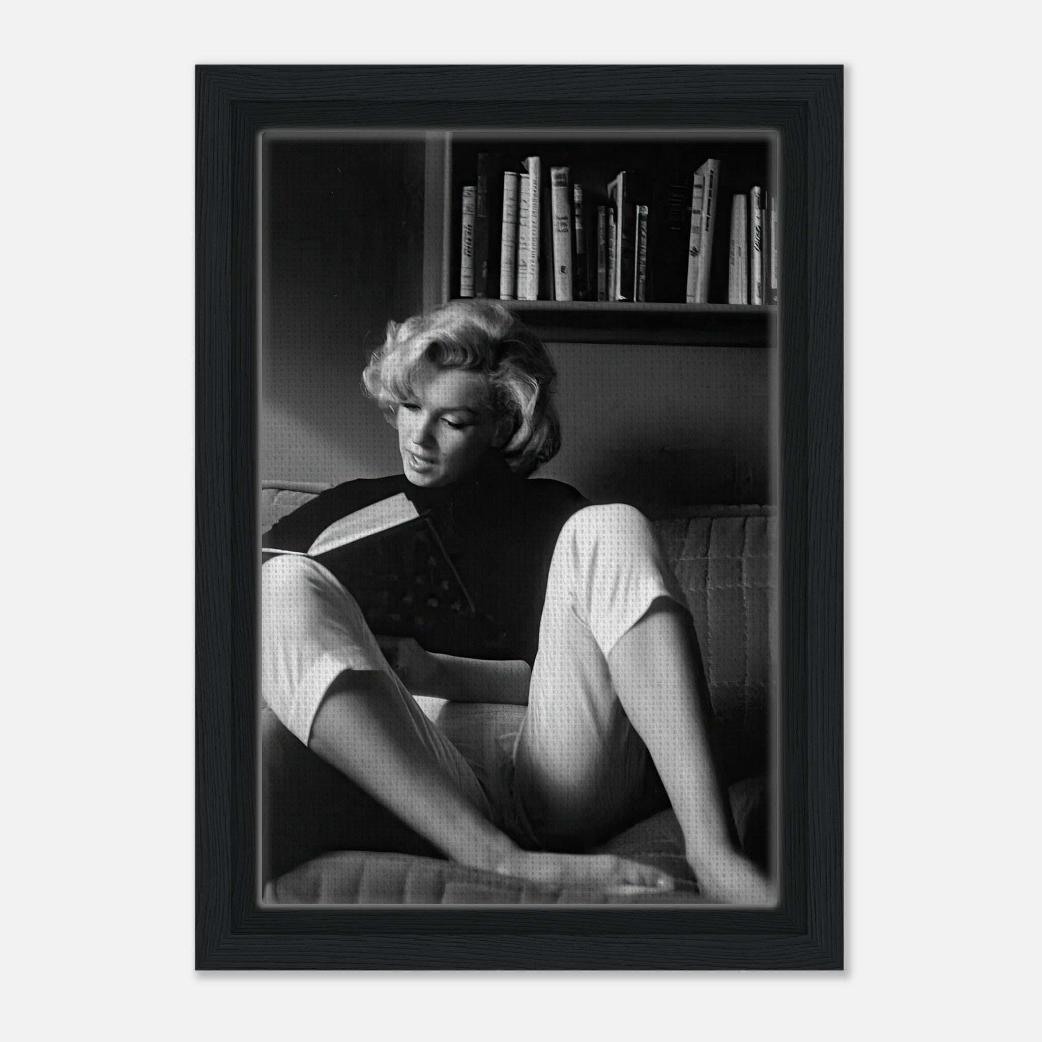 Marilyn Monroe reading a book at home, featured in a black-and-white framed canvas print.