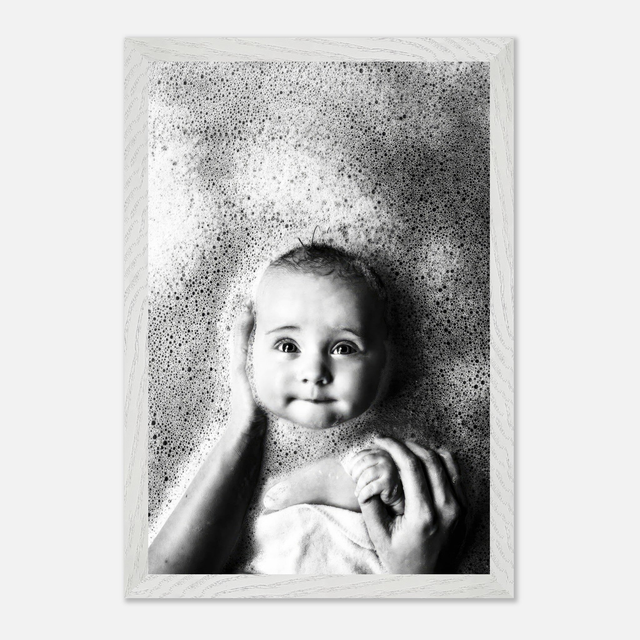 Black-and-white fine art photo of a baby in a bath with soft bubbles, capturing childhood innocence and joy.