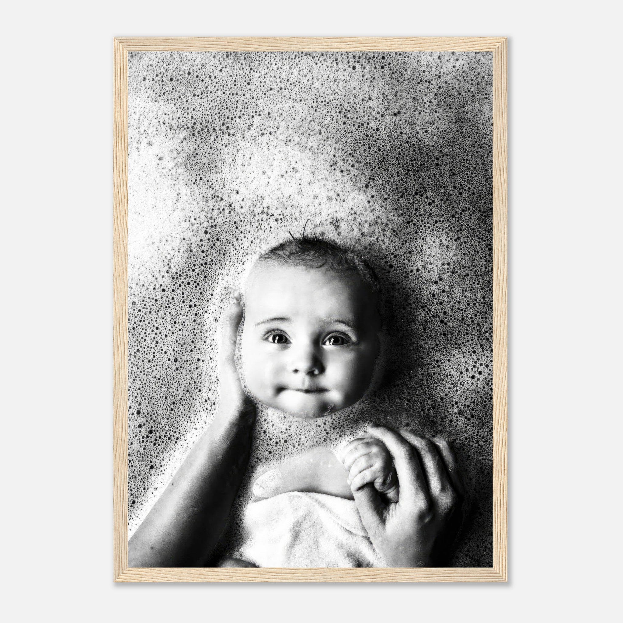 Framed print of a baby smiling amidst bubbles, capturing the joy and innocence of bath time in black-and-white photography.