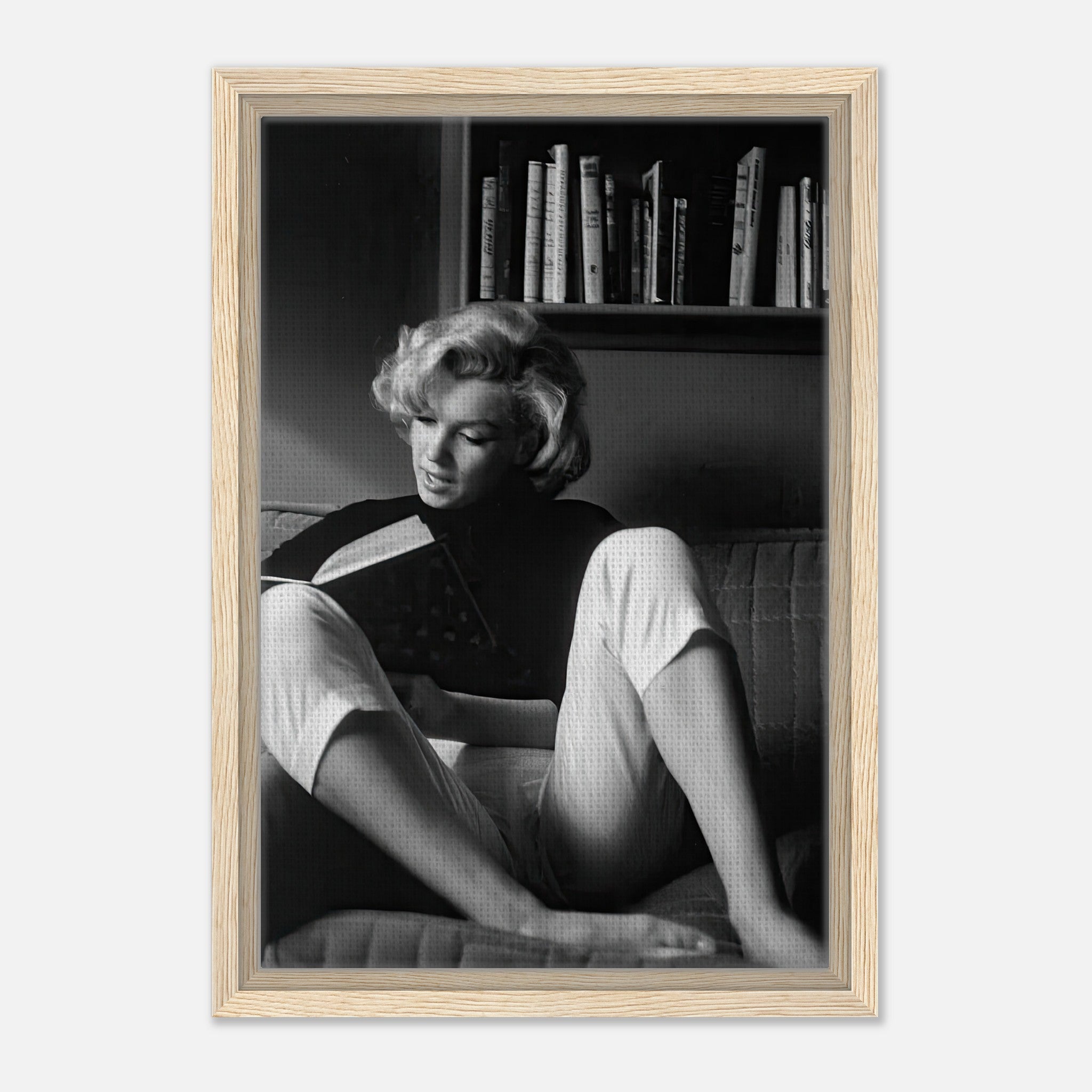 Marilyn Monroe reading at home in black-and-white, framed canvas art with light wood finish.