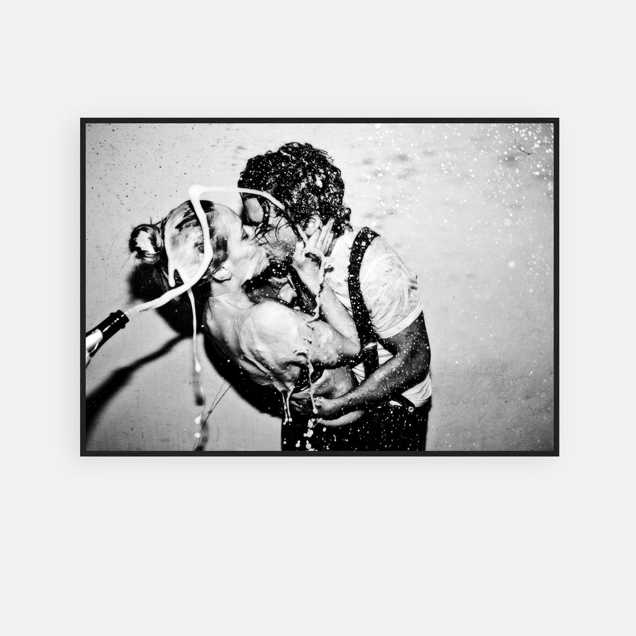 Black-and-white framed print of passionate kiss with champagne explosion, featuring iconic couple.