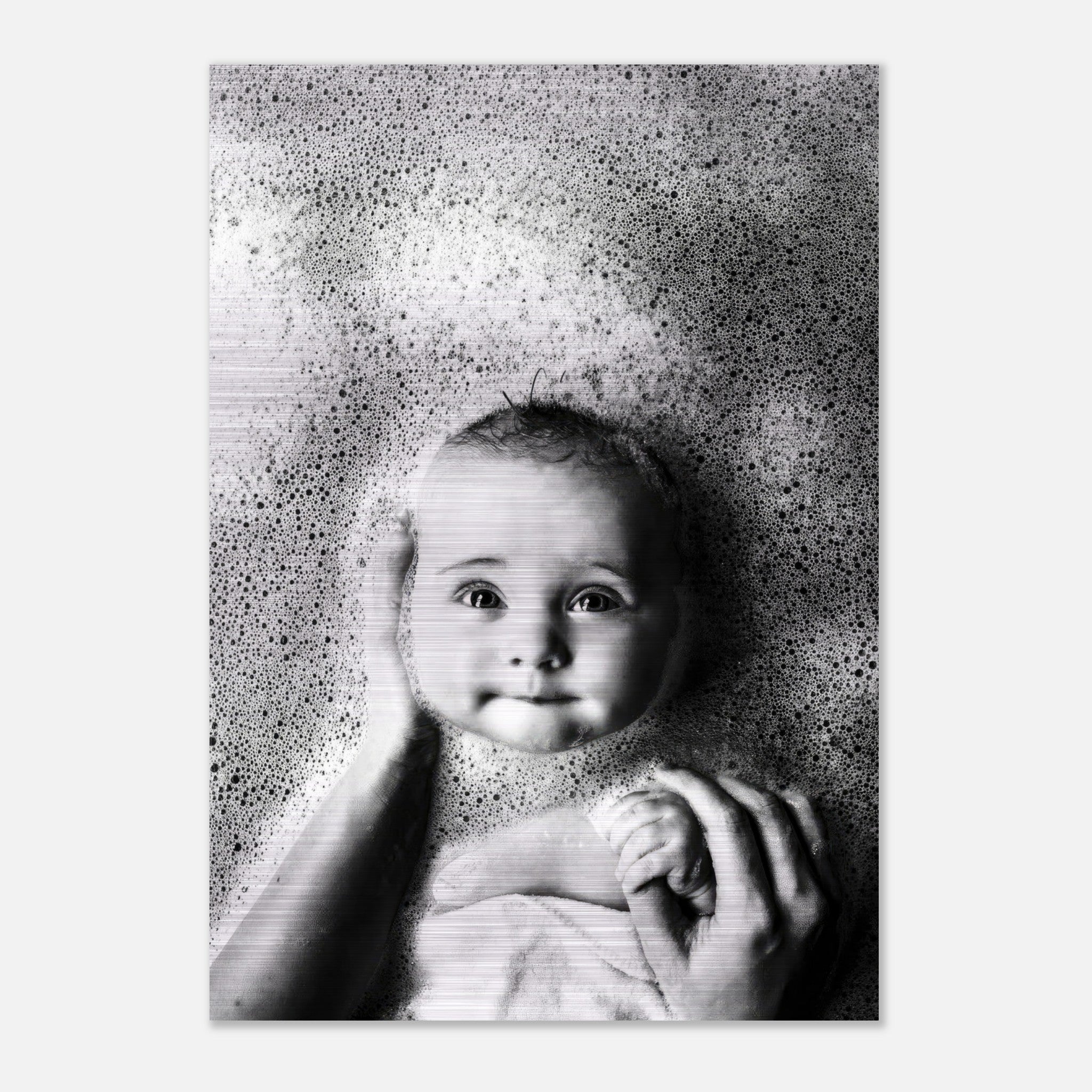 Black and white photo of a baby surrounded by bubbles, showcasing pure joy during bath time on brushed metal.