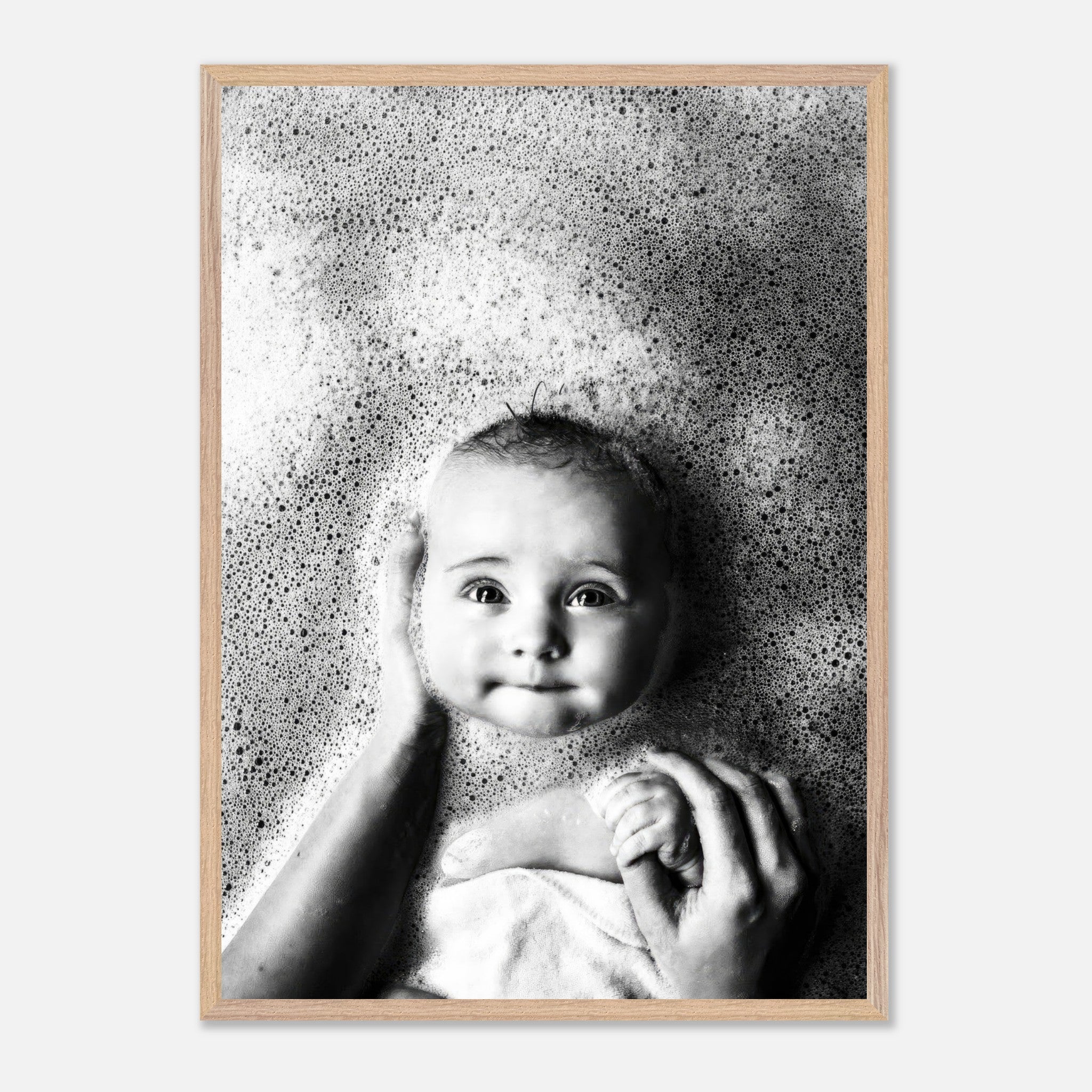 Black-and-white fine art print of a smiling baby in a bubble bath, capturing innocence and joy.