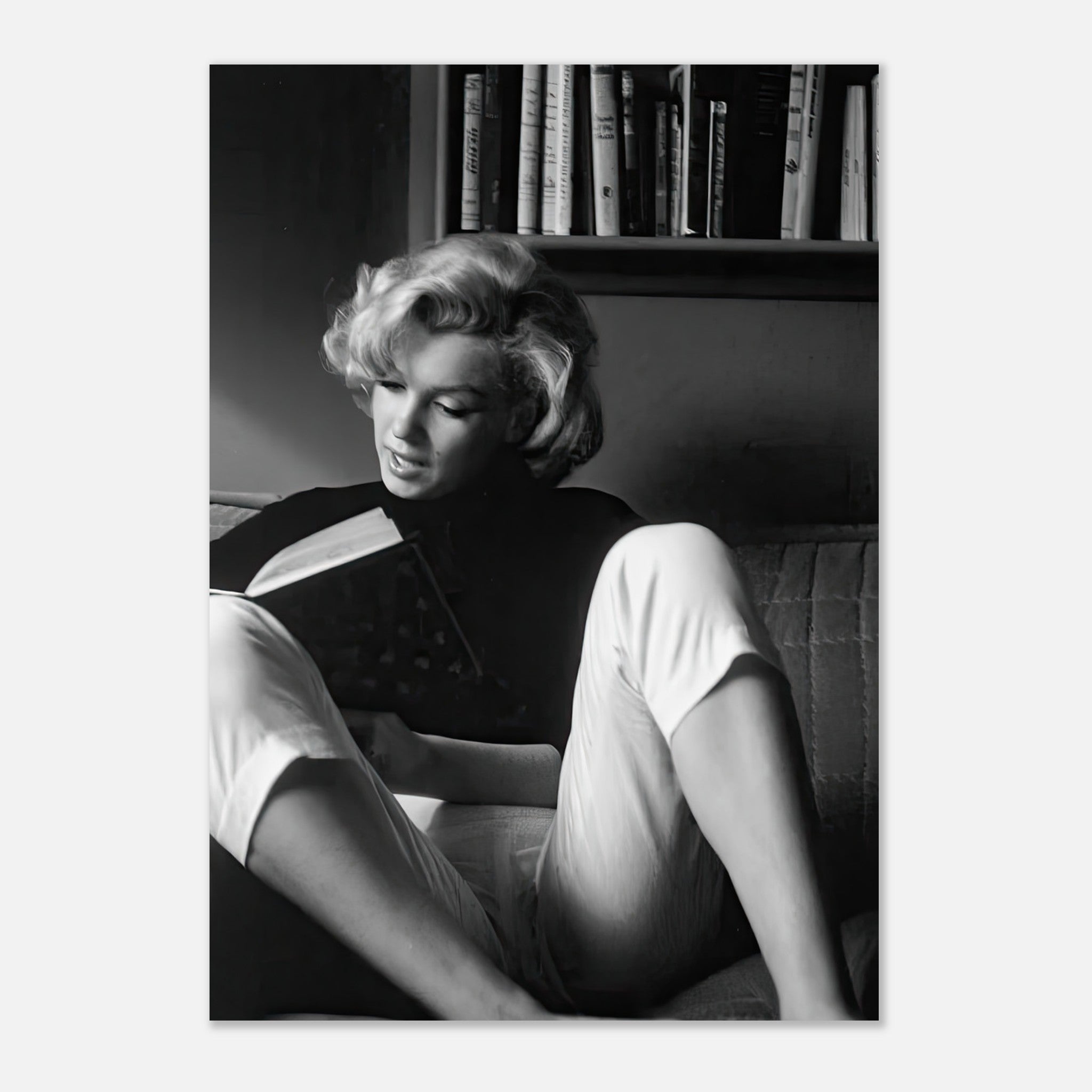 Marilyn Monroe reading at home in black-and-white, showcasing elegance and charm in a cozy setting.