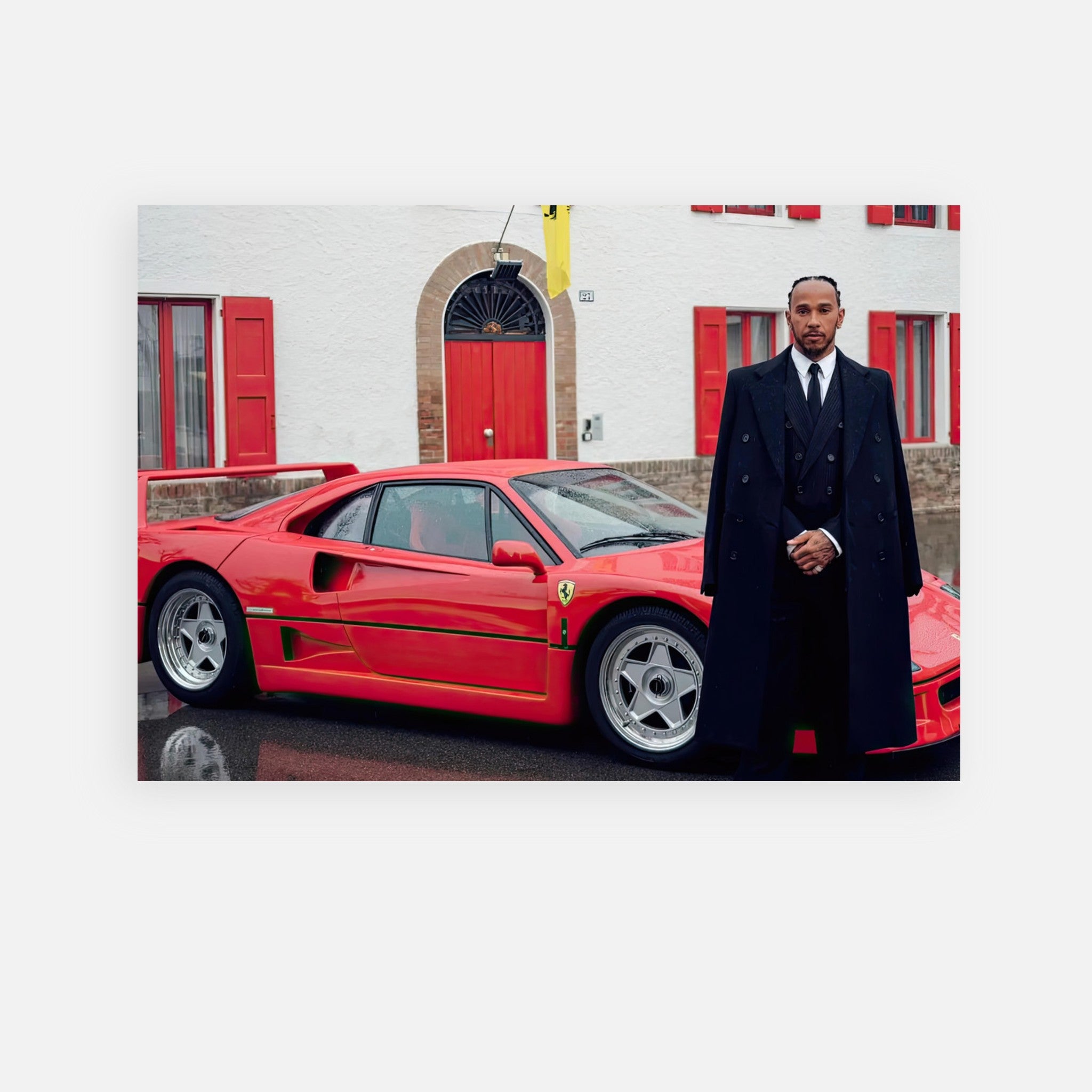 Lewis Hamilton in a stylish outfit beside a red Ferrari F40, showcasing automotive excellence in front of Enzo Ferrari's home.