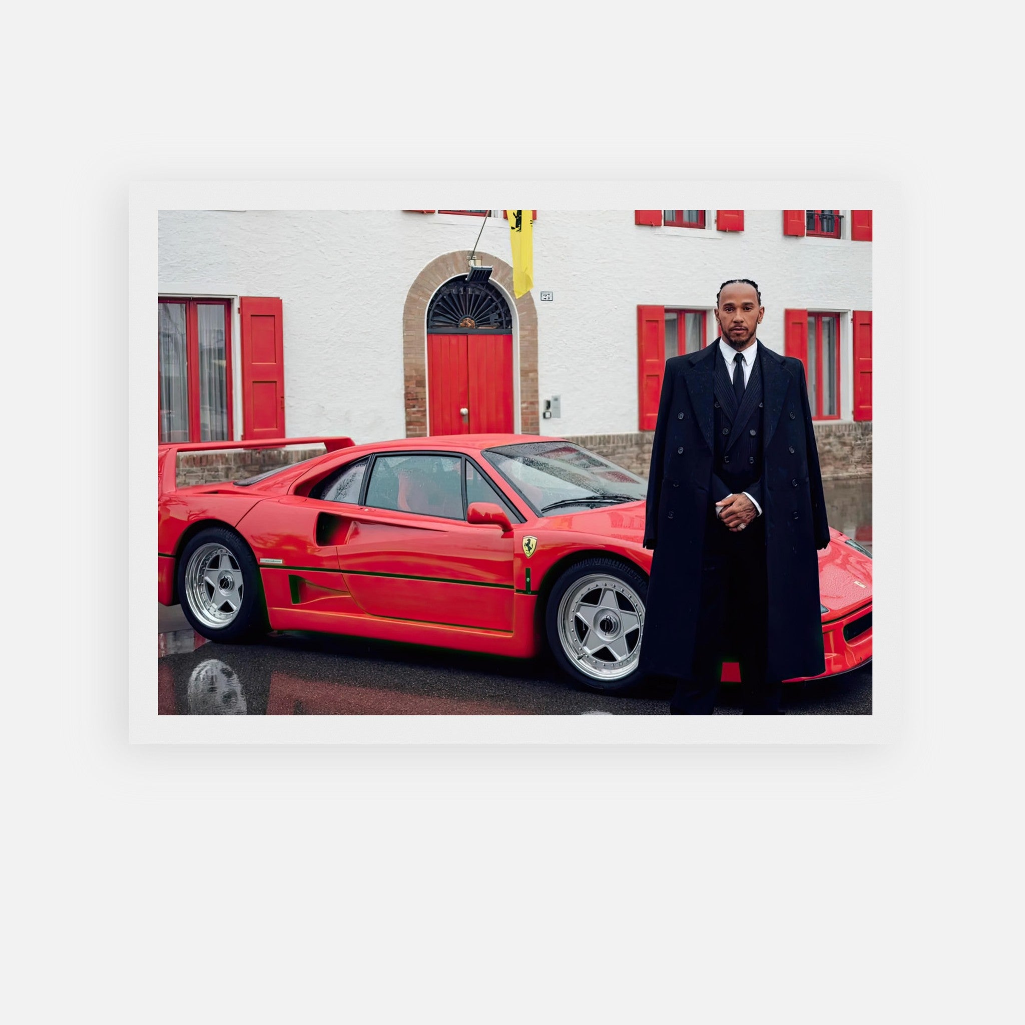 Lewis Hamilton standing next to a red Ferrari F40, posed in front of Enzo Ferrari's house.