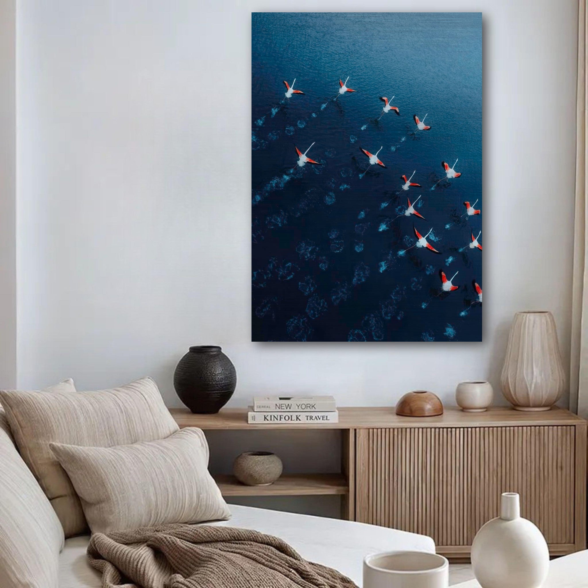 Flamingos drone photography brushed metal print in modern living room with aerial view of pink flamingos over blue water.