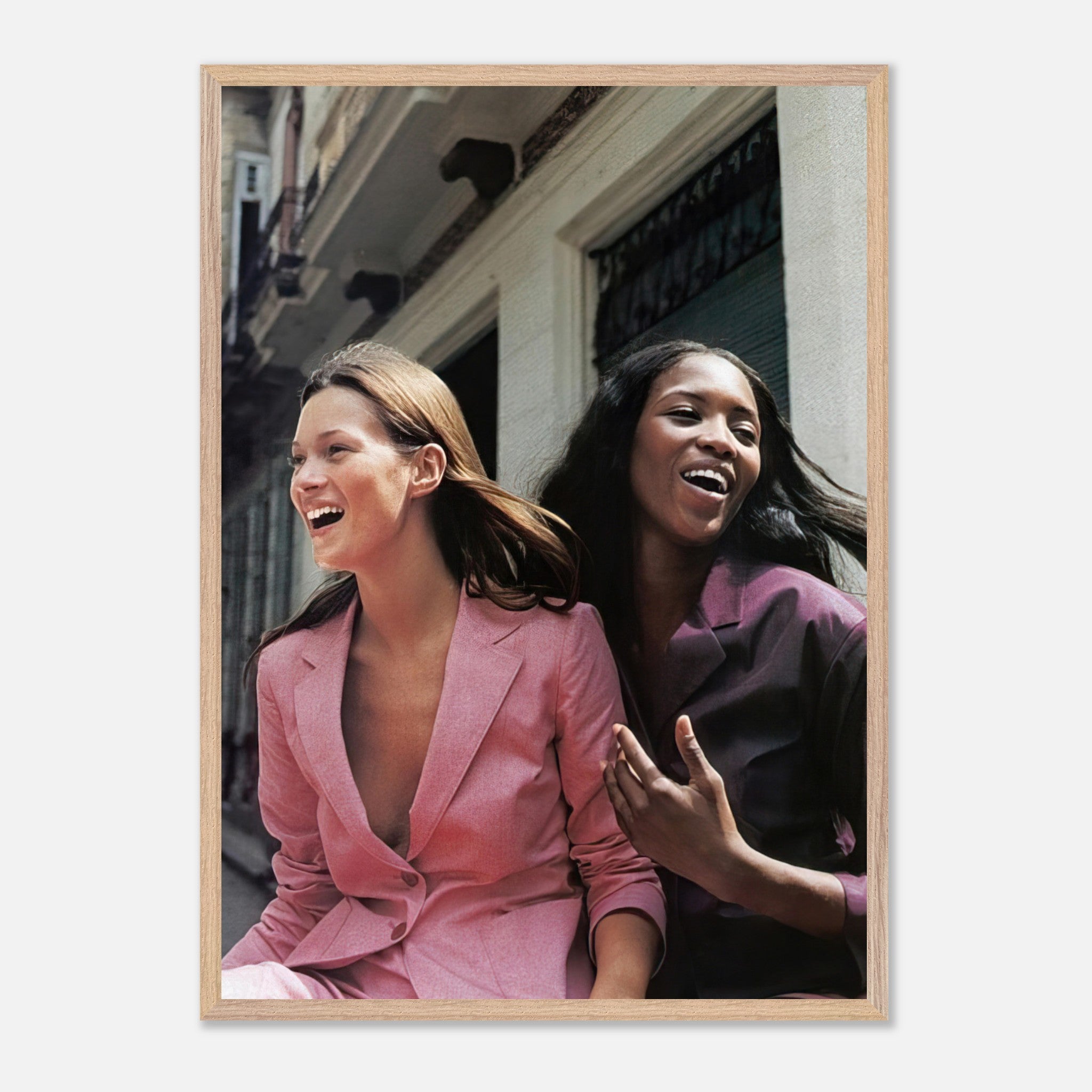 Naomi Campbell and Kate Moss laughing in stylish outfits, capturing the essence of high fashion and friendship.