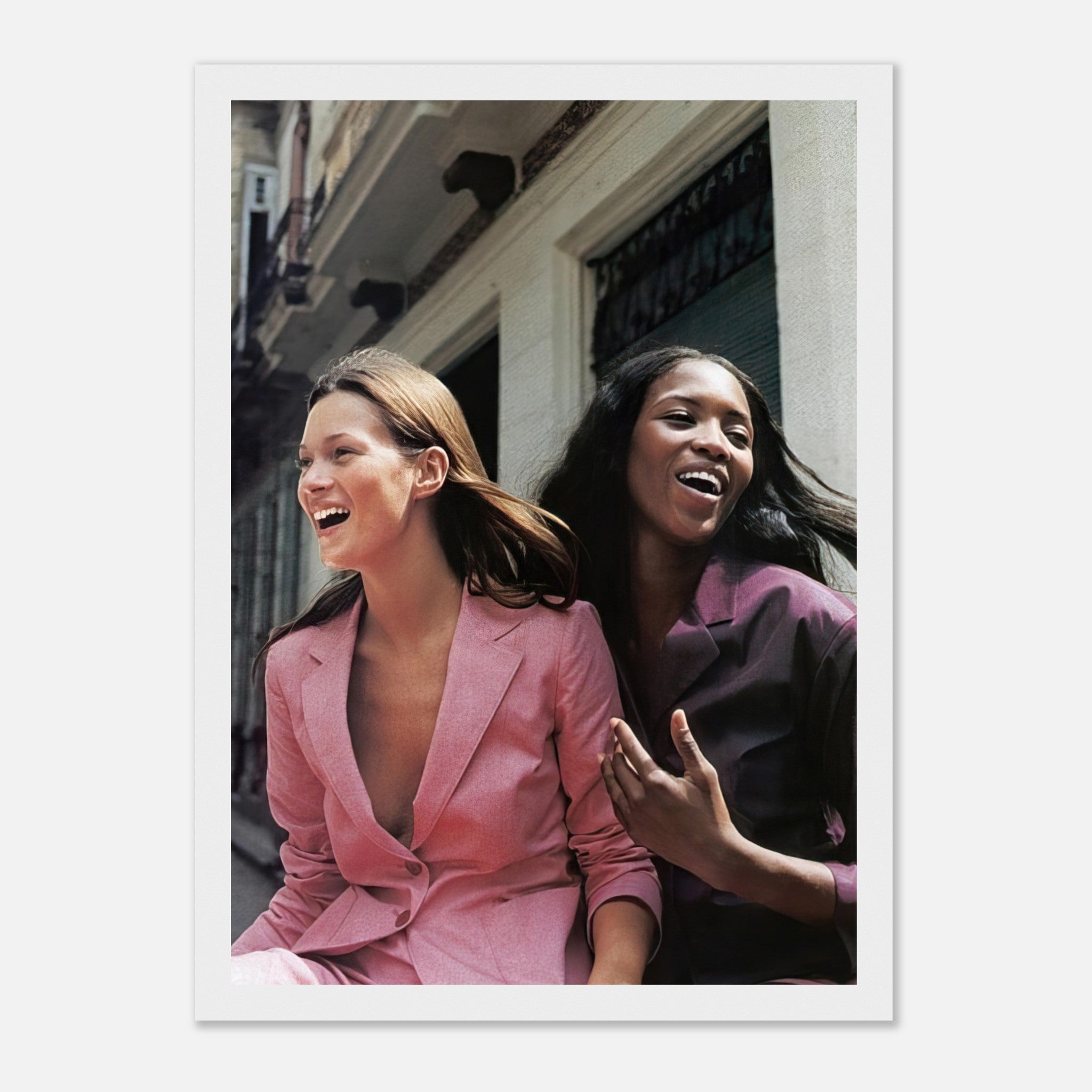 Naomi Campbell and Kate Moss laughing together in elegant suits, capturing the essence of iconic fashion moments.