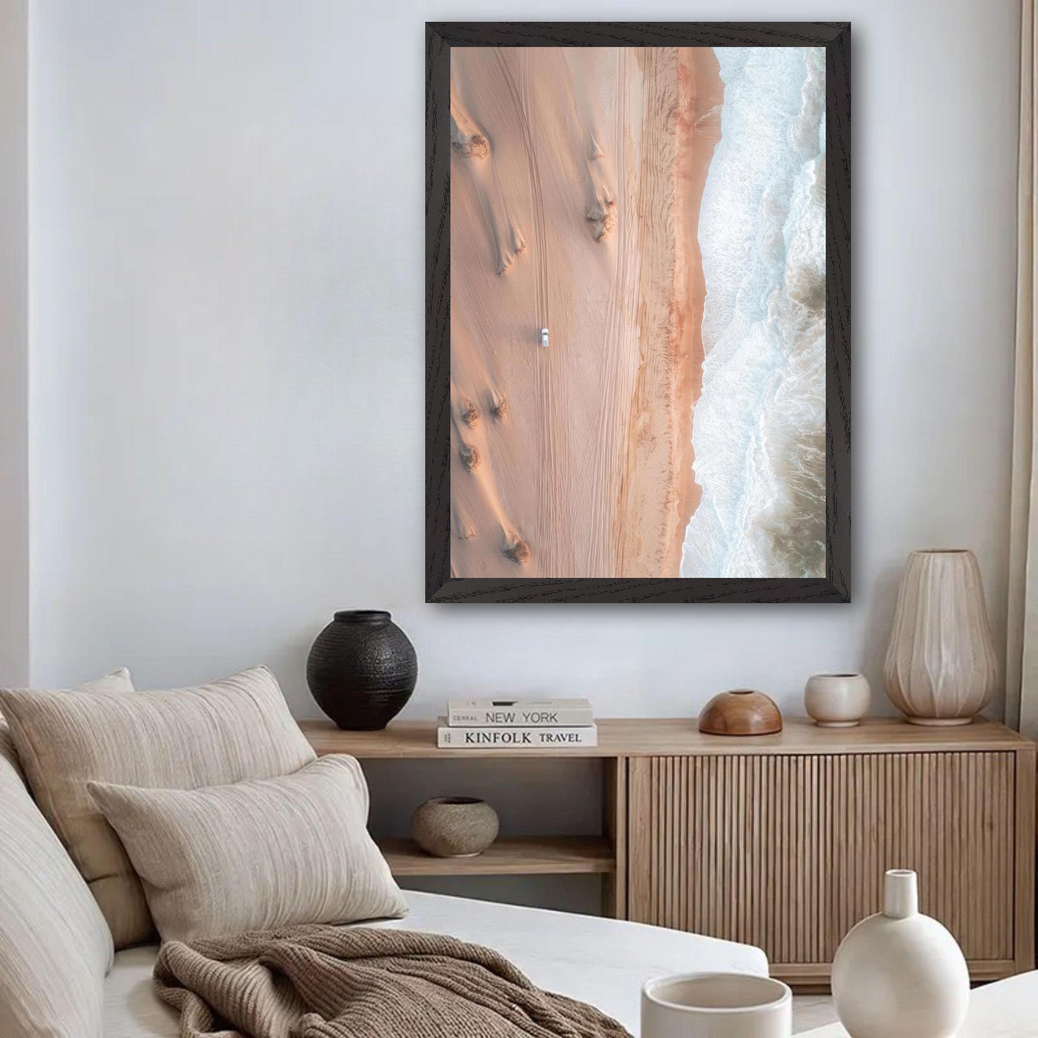 Drone photography vintage print of desert and ocean with a lone vehicle in a modern interior setting.