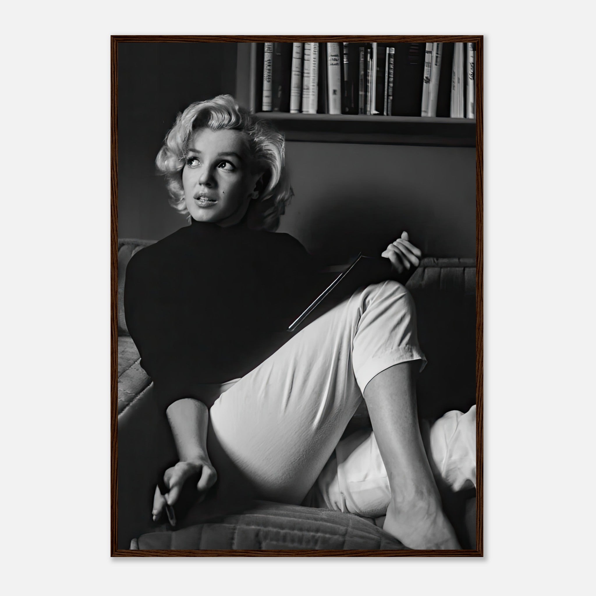 Marilyn Monroe reading a book in a cozy setting, captured in elegant black-and-white framed print.
