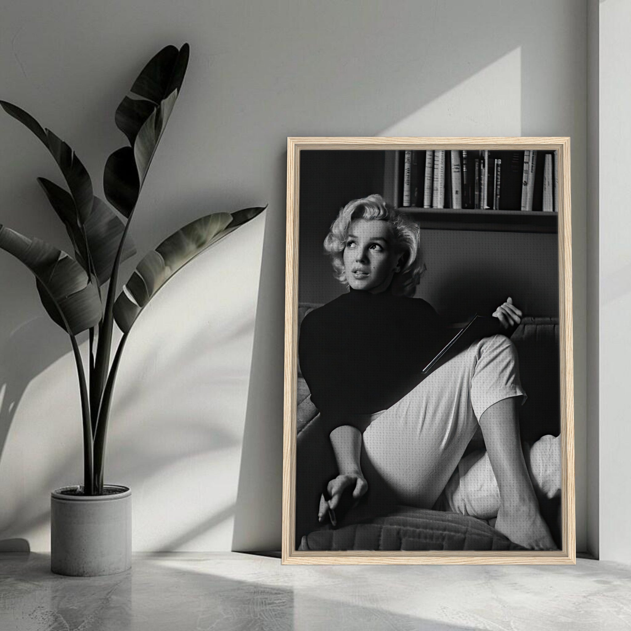 Black-and-white framed canvas print of Marilyn Monroe reading a book in a stylish interior setting.