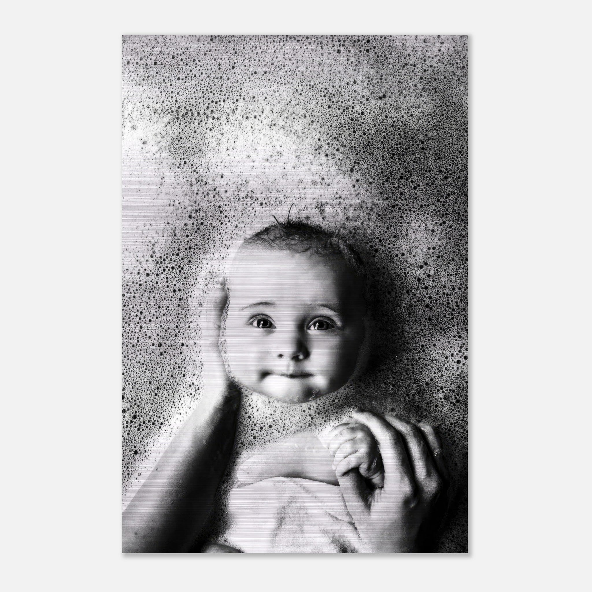 Black and white baby bath photograph on brushed metal, capturing innocence with bubbles and a serene expression.