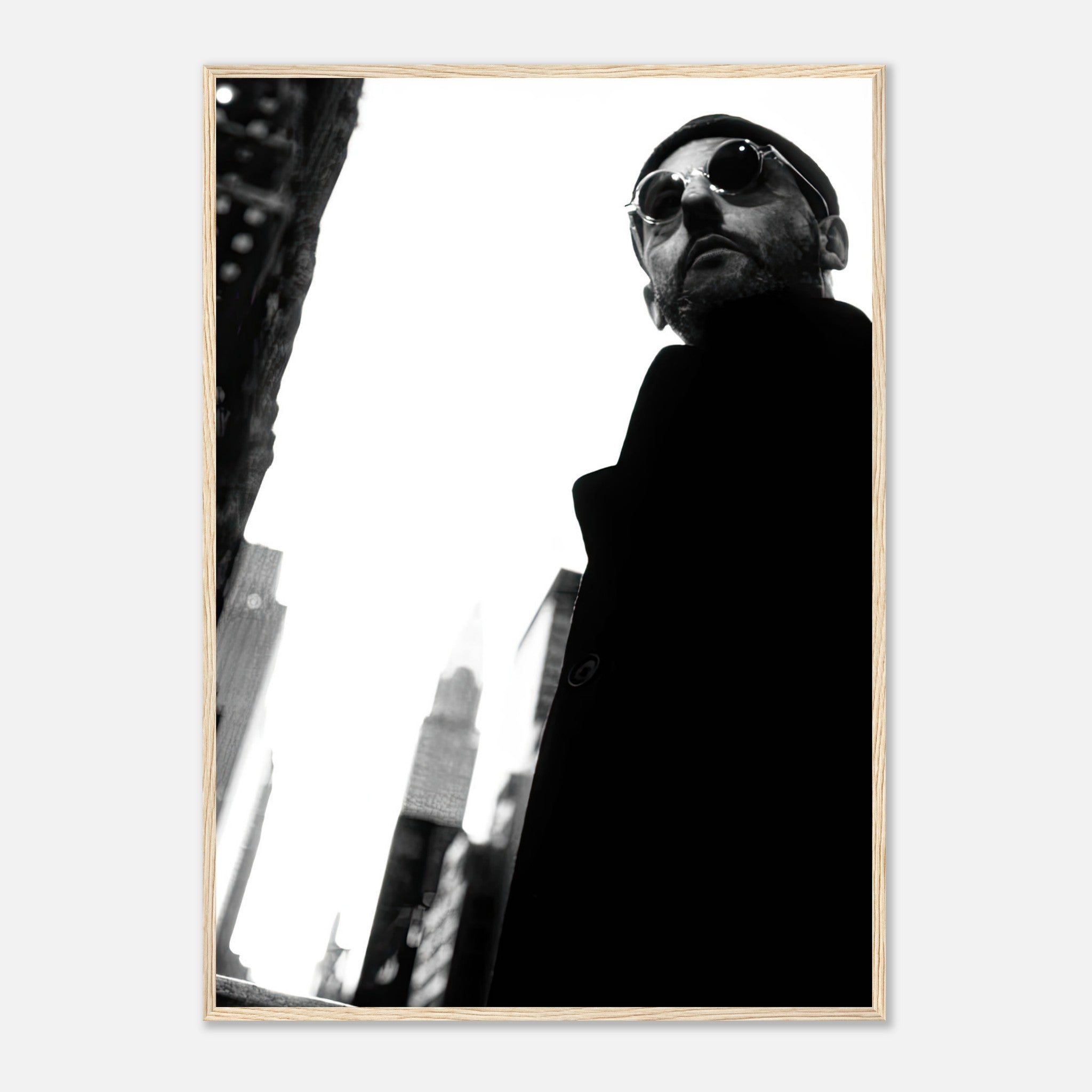 Jean Reno framed print in black-and-white, featuring an urban backdrop and stylish sunglasses, perfect for cinematic decor.