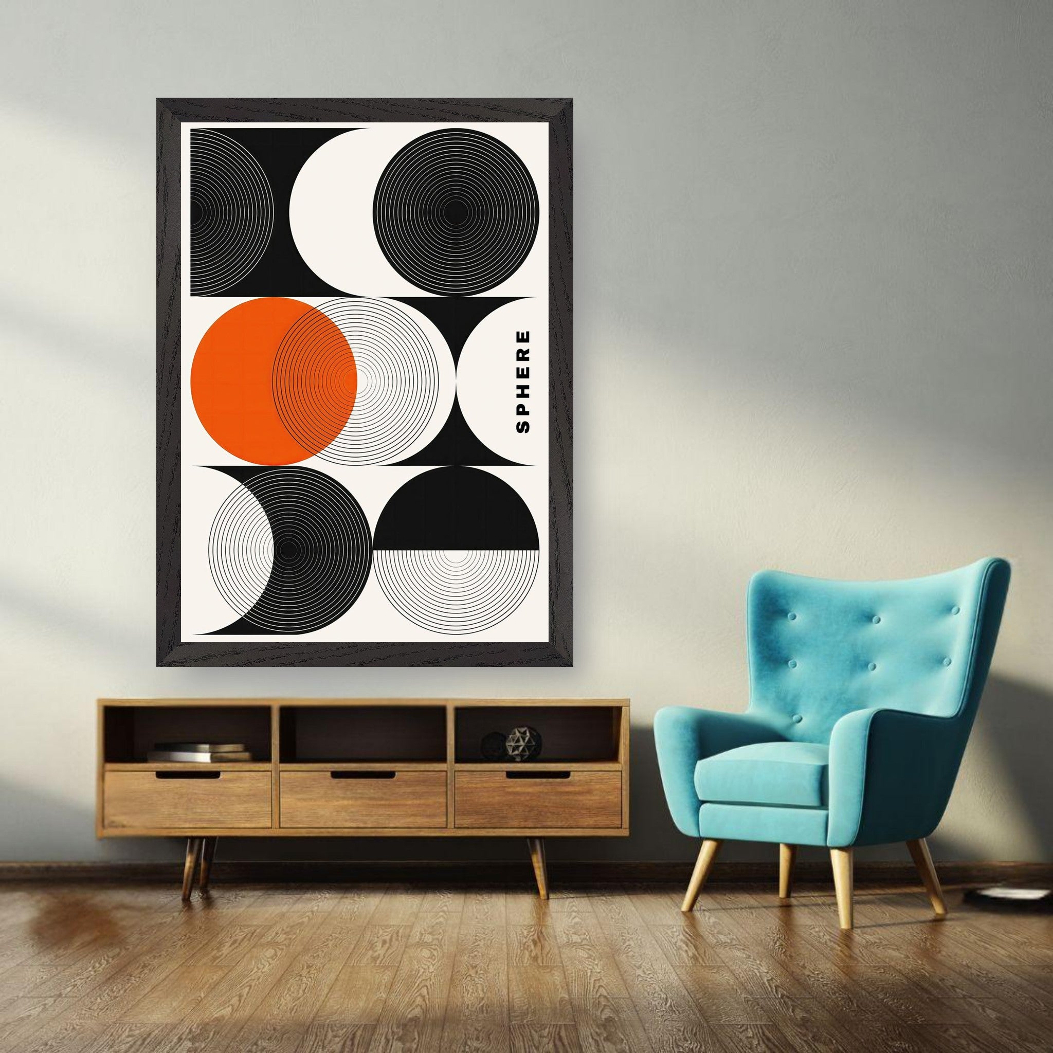 Abstract geometric sphere art framed print in black, white, and orange on wall next to teal chair and wooden cabinet.