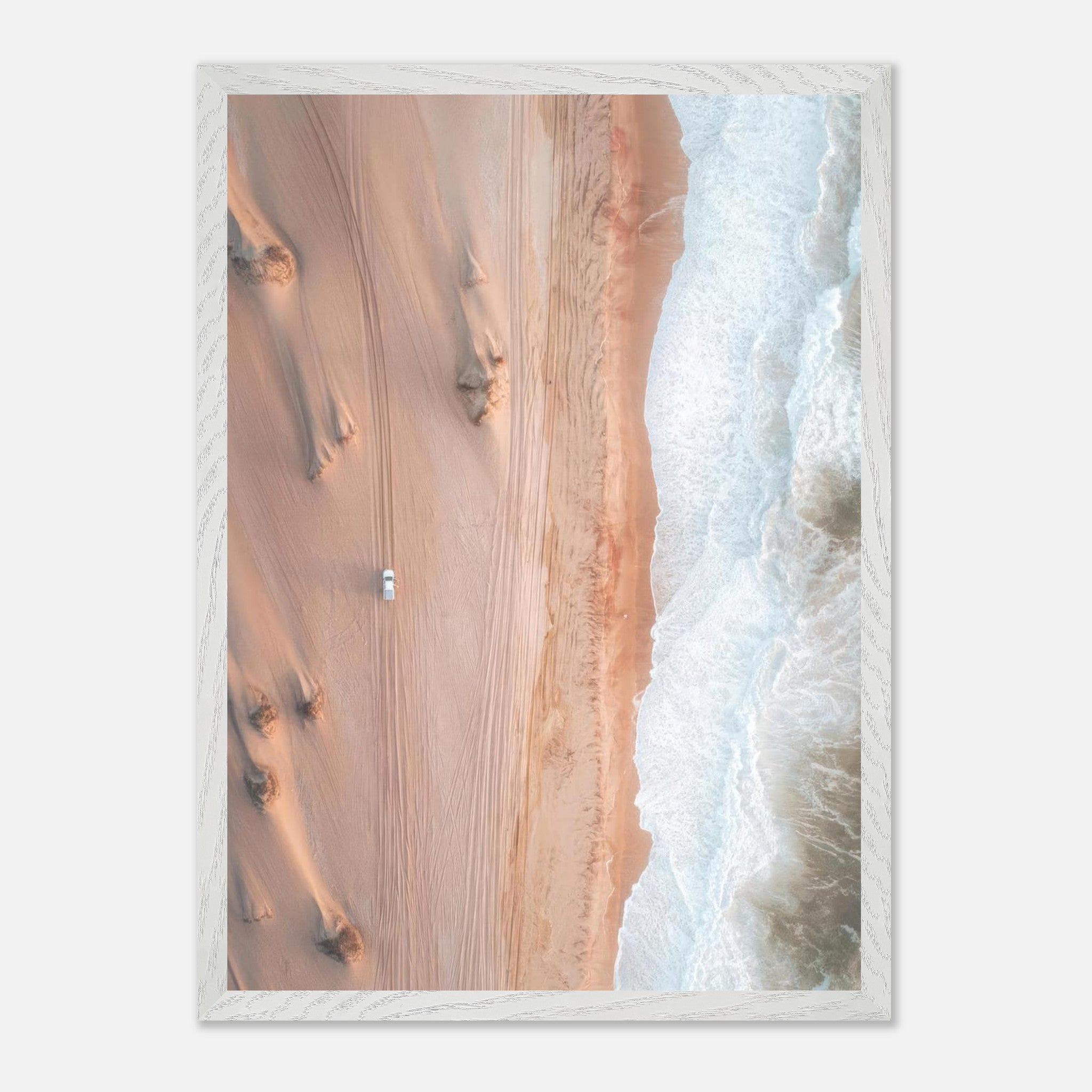 Drone photography print showcasing a desert meeting the ocean with a lone vehicle on sandy dunes.