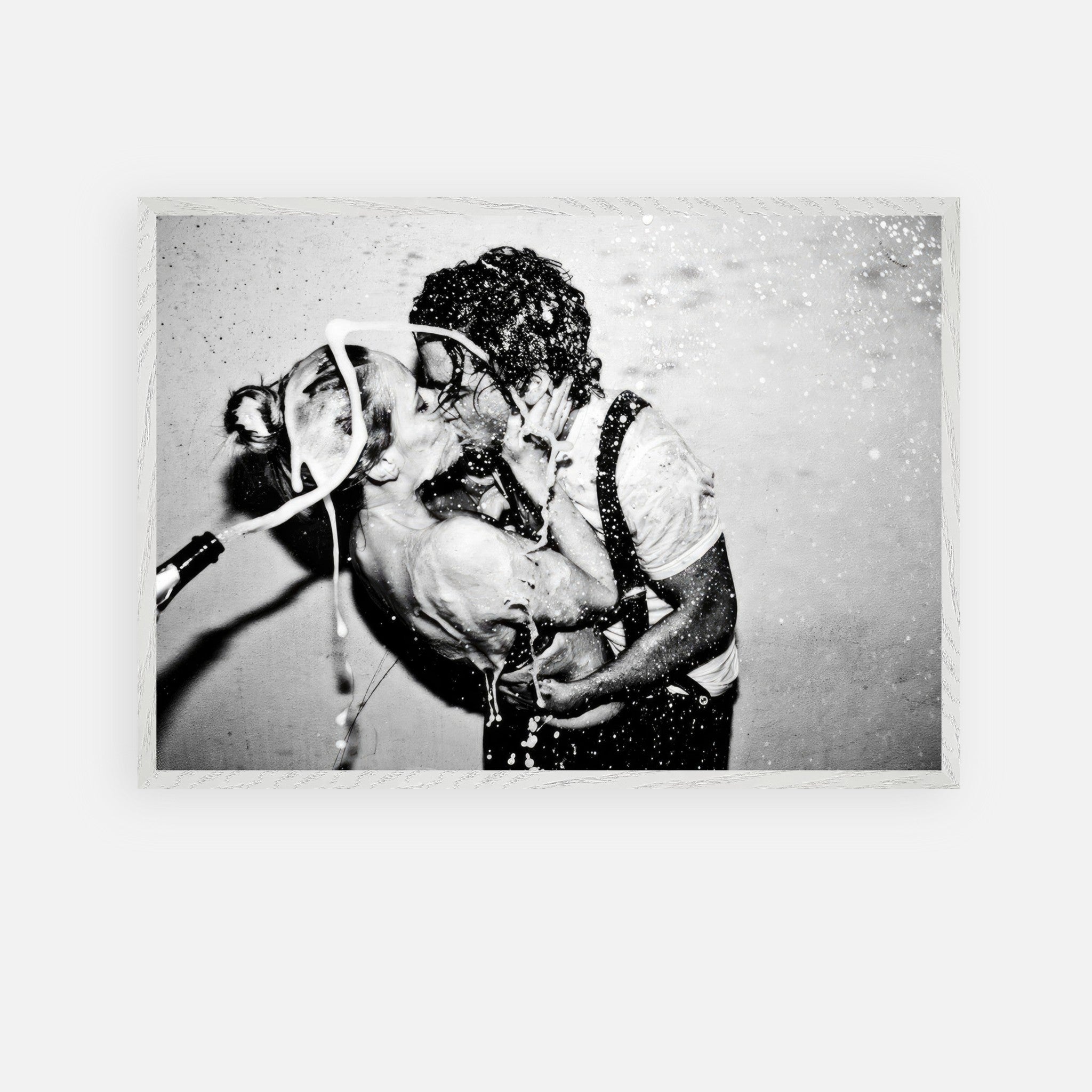 Vintage black-and-white photo of Johnny Depp and Kate Moss sharing a passionate kiss with champagne celebration.