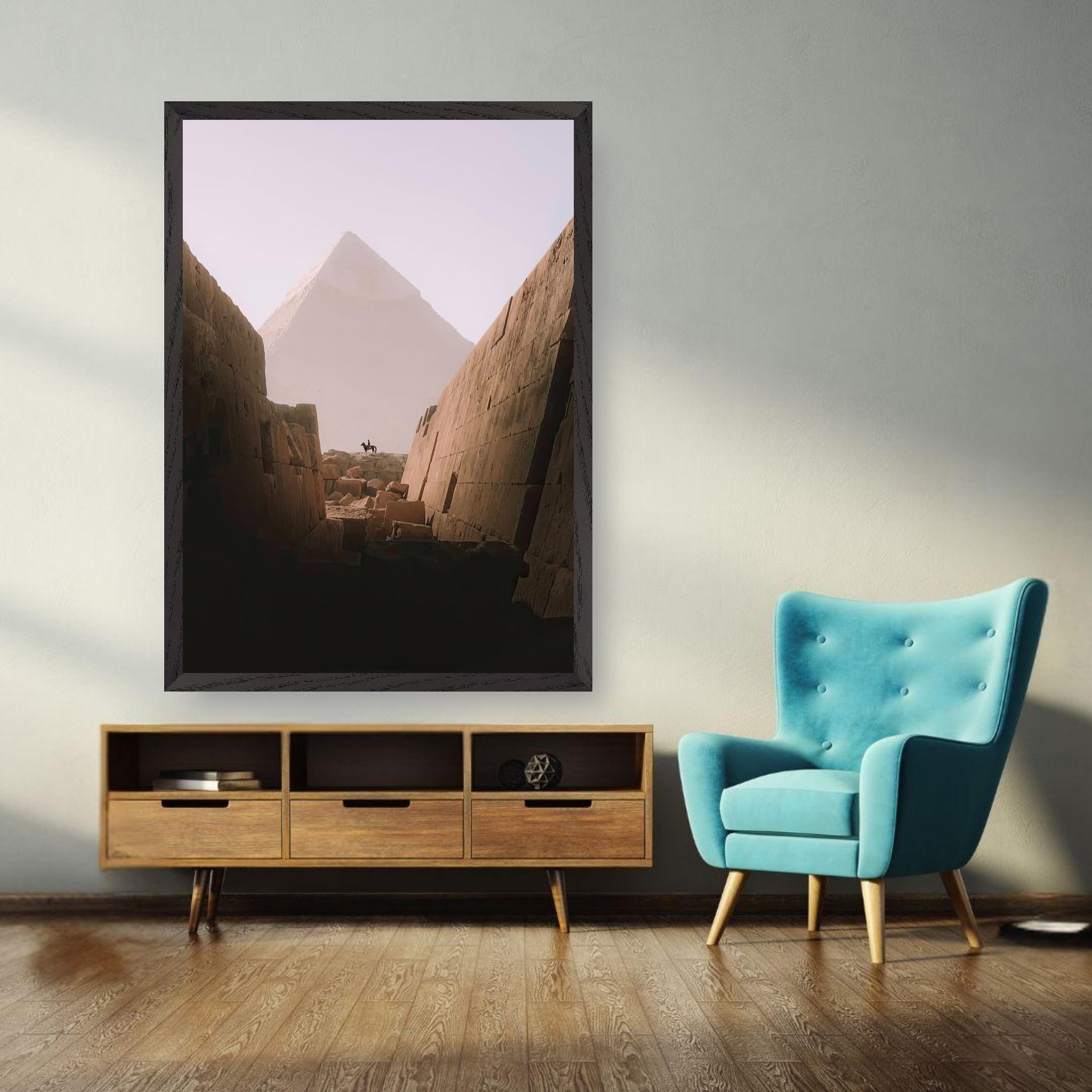 Fine art print of the Great Pyramid of Giza hanging on a wall in a stylish room with teal chair and wooden furniture.