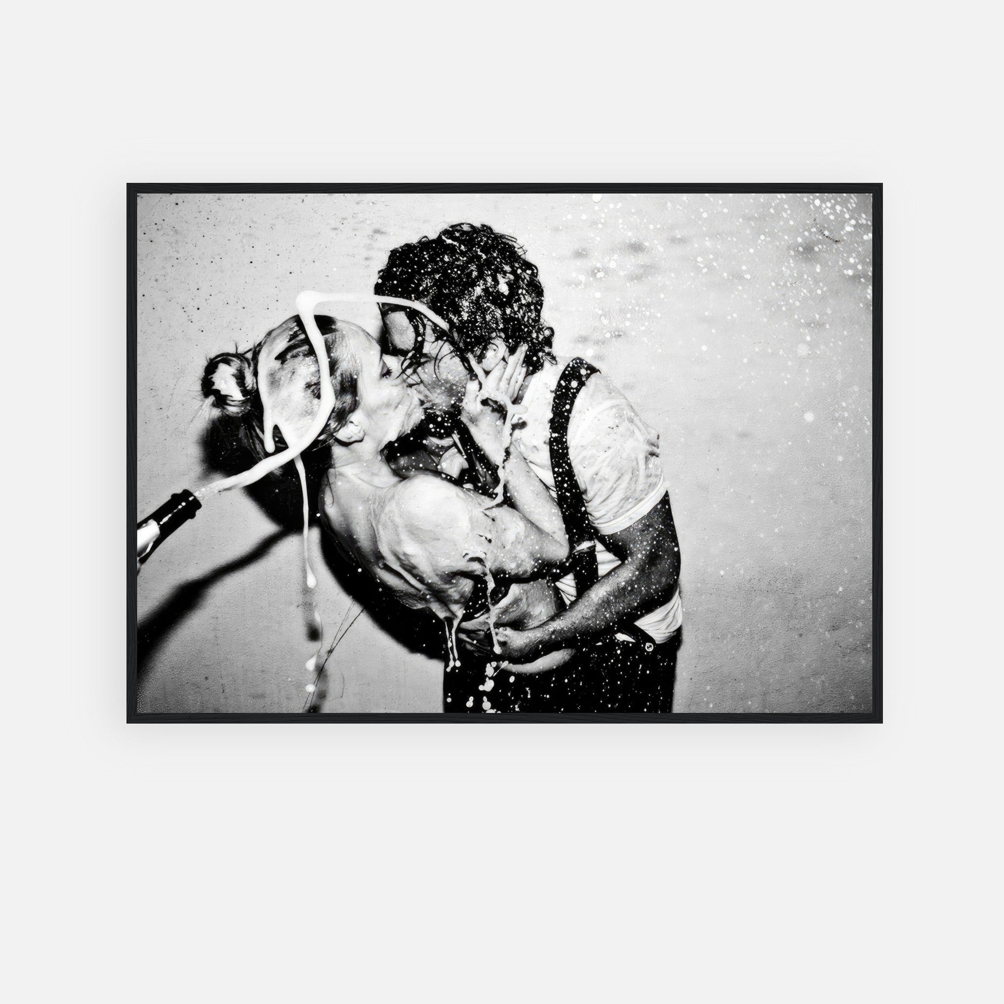 Black-and-white framed print of passionate kiss between couple with champagne splashing.