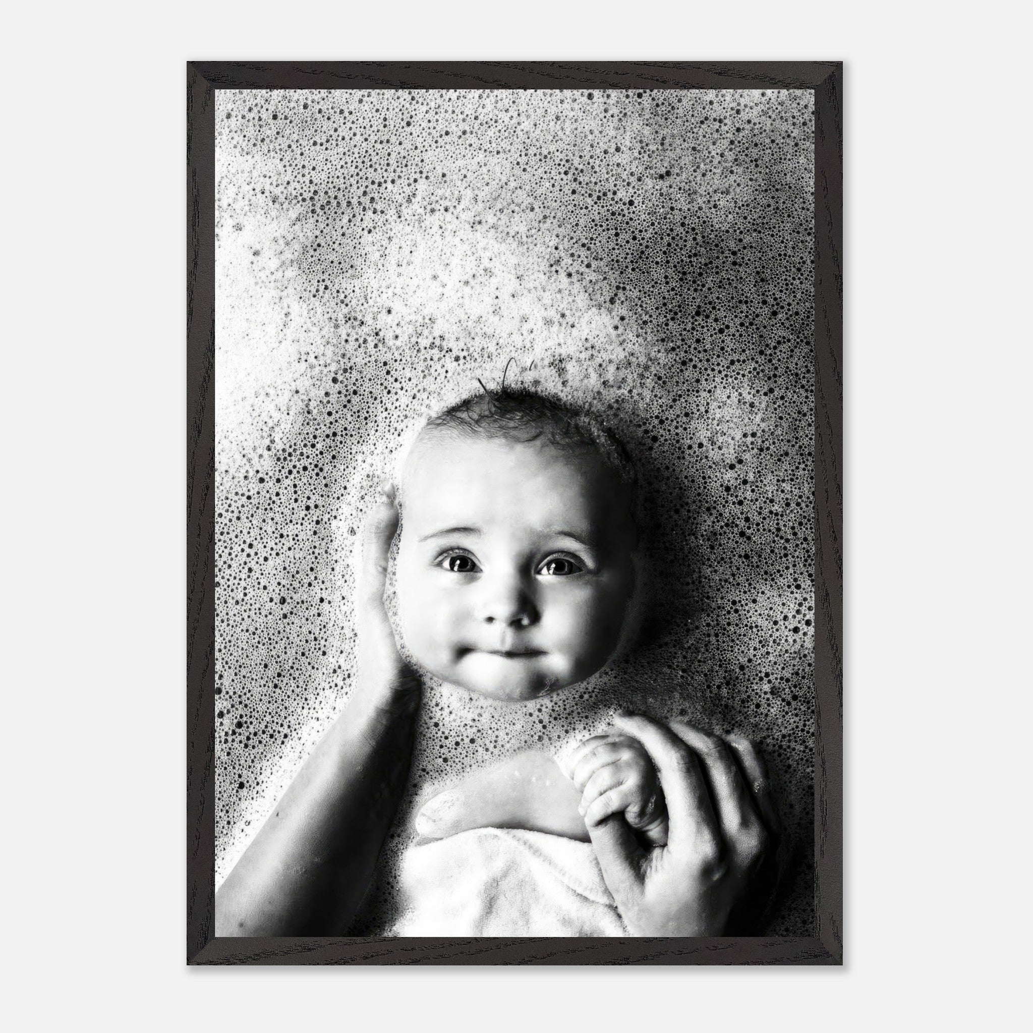 Vintage black and white photograph of a smiling baby in a bubble bath, framed in a classic black frame.