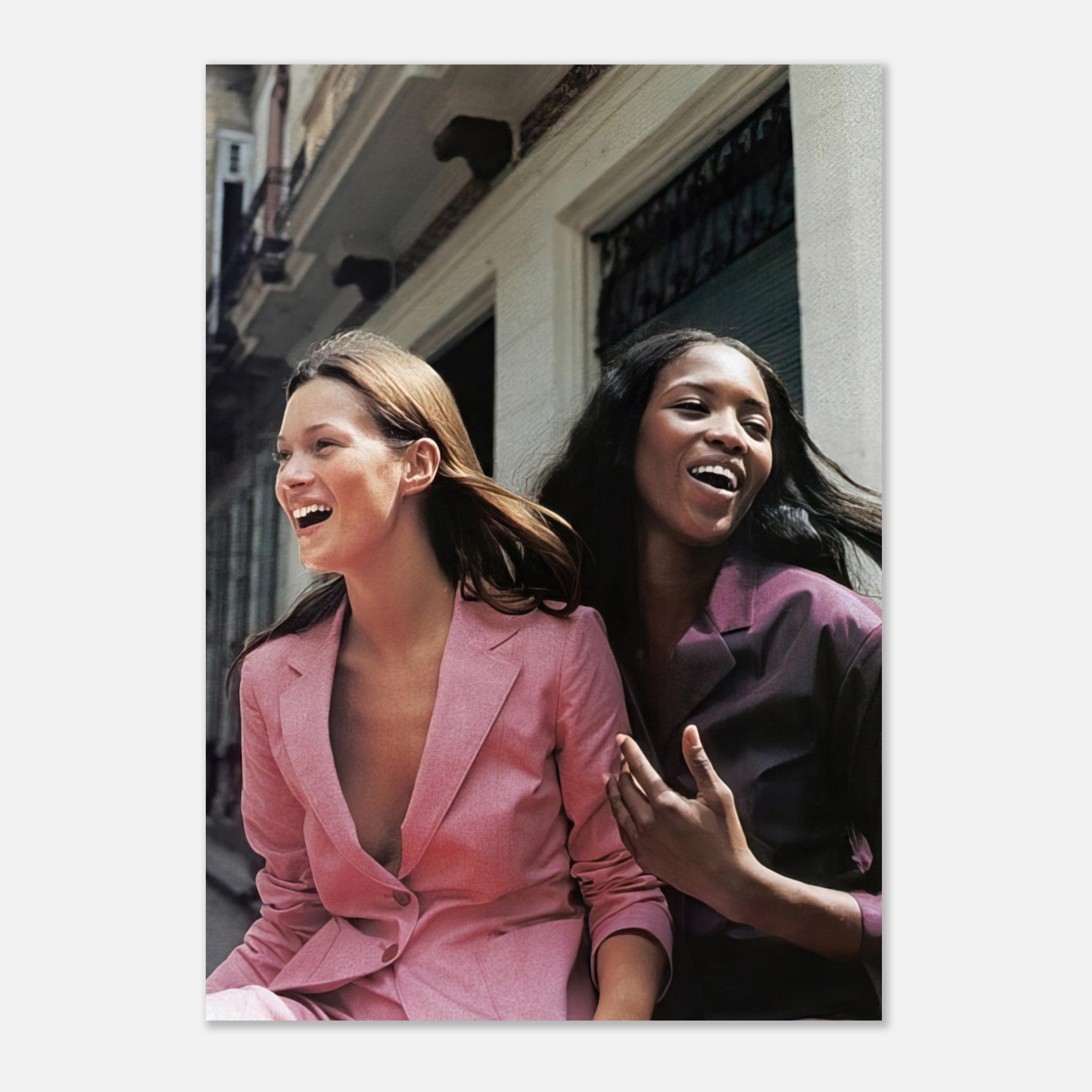 Naomi Campbell and Kate Moss laughing together in stylish outfits, showcasing timeless fashion in a vibrant poster.