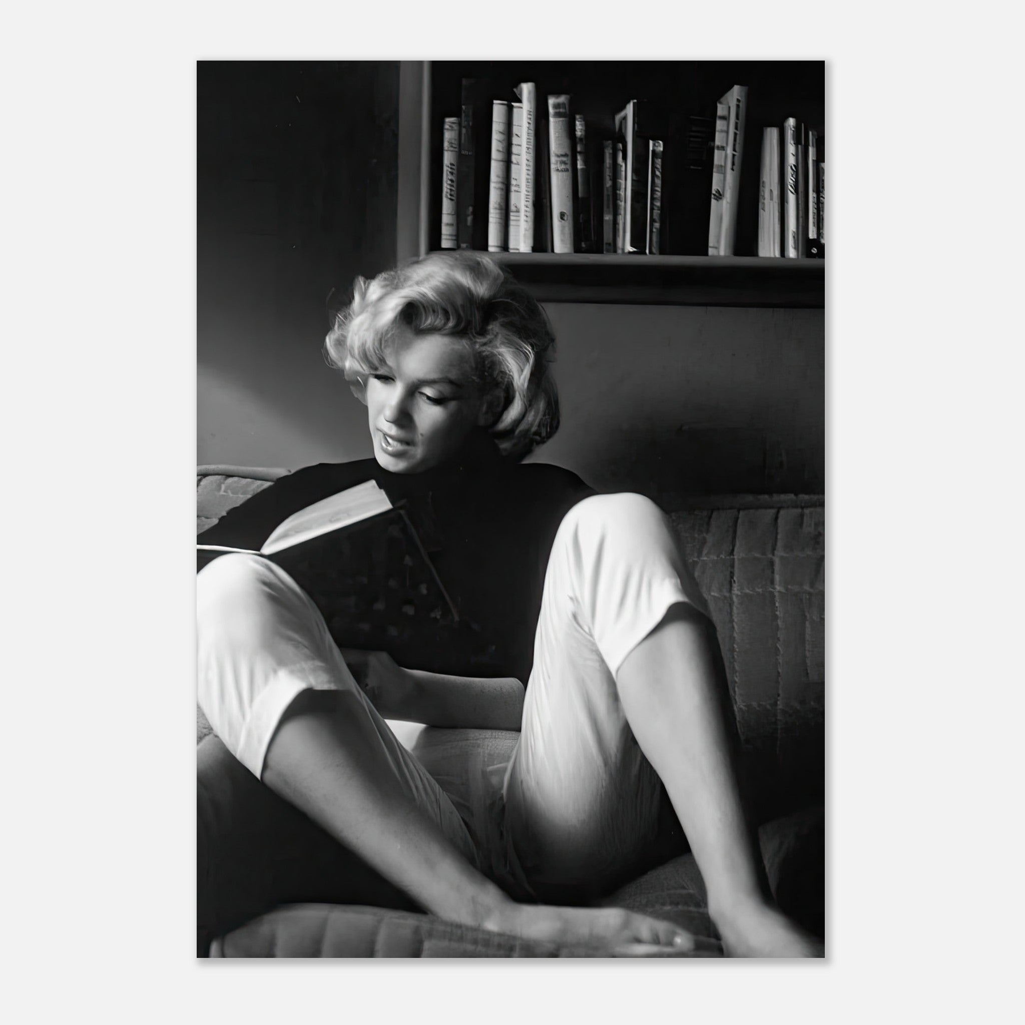 Marilyn Monroe reading a book on a sofa, captured in a classic black-and-white poster.