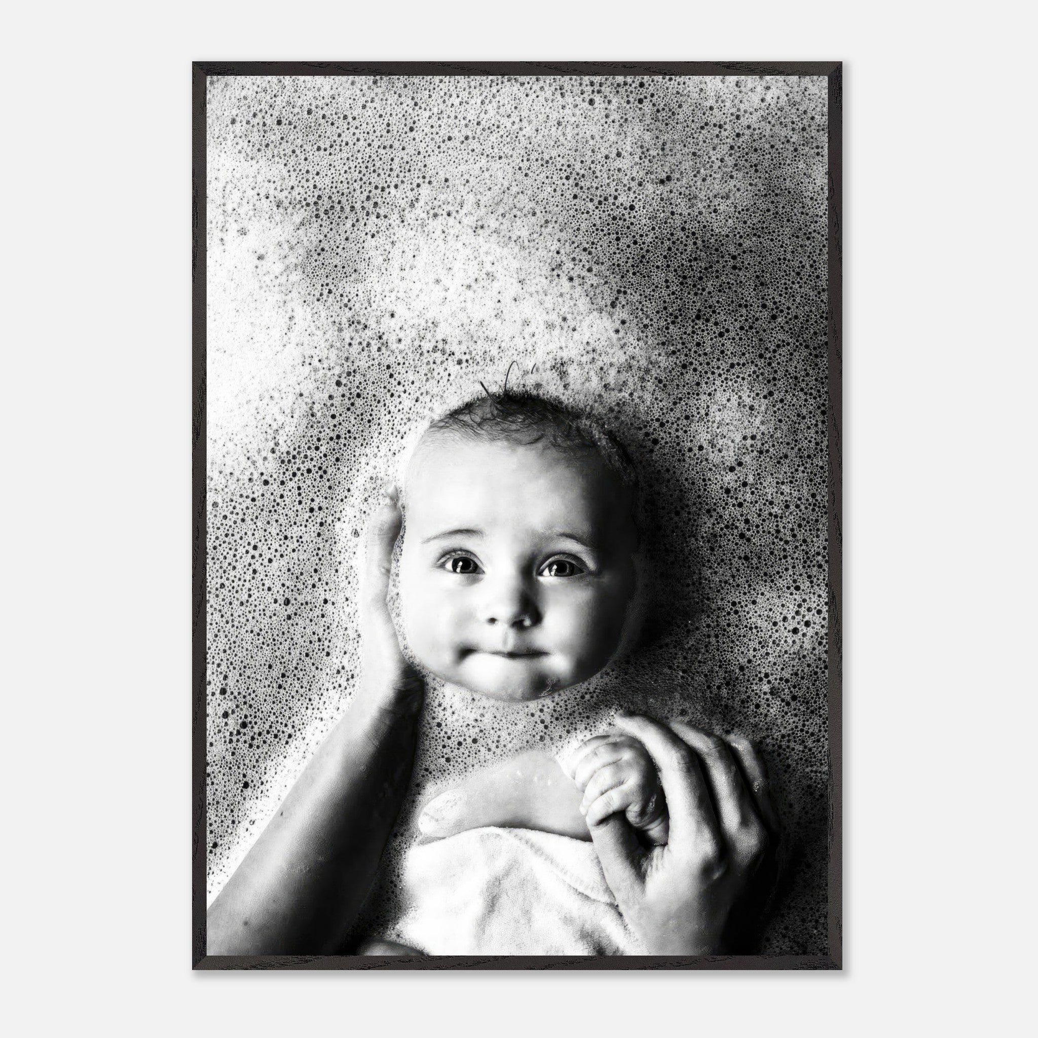 Black-and-white fine art print of a smiling baby in a bubble bath, showcasing innocence and joy.