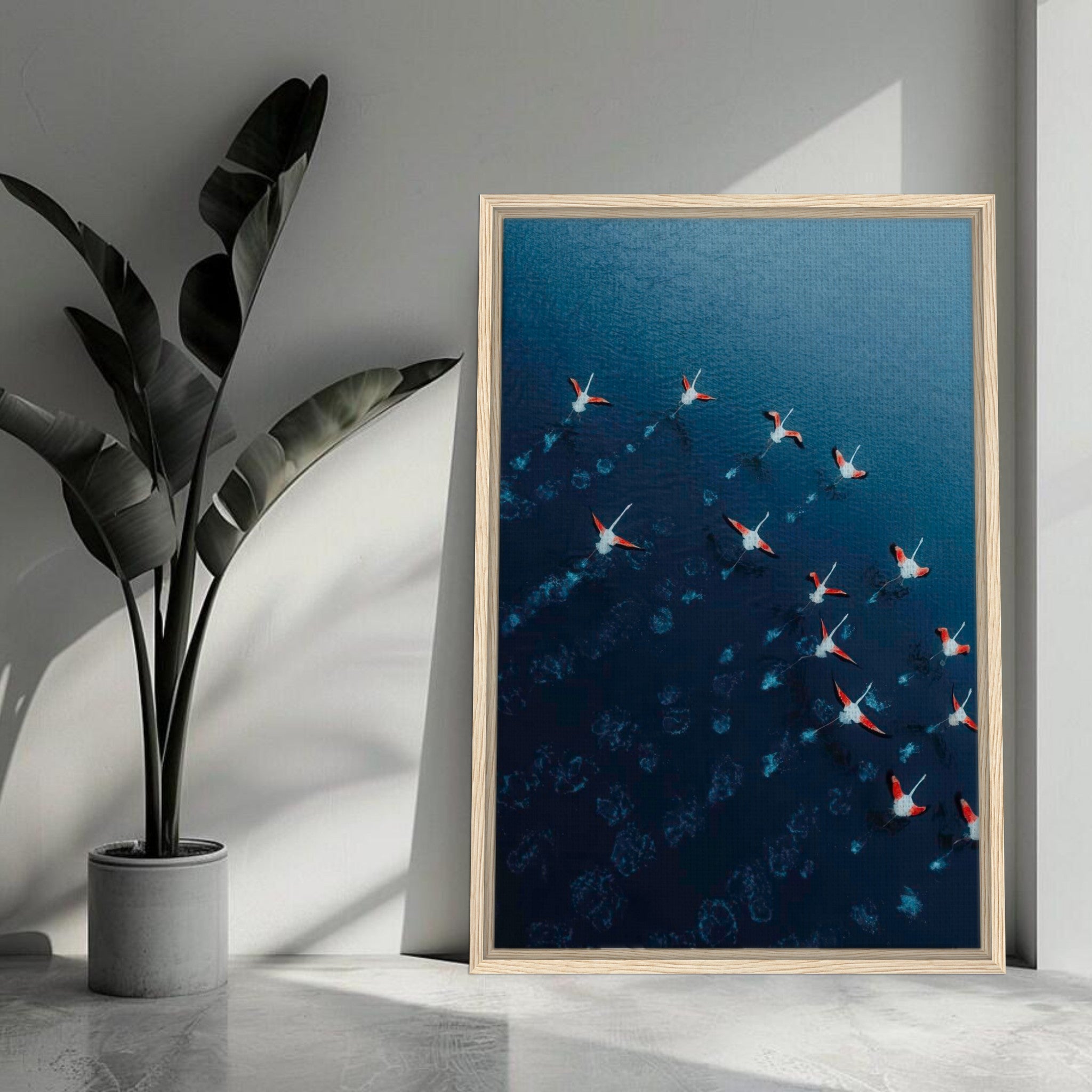 Framed canvas print of aerial drone photography featuring flamingos in flight over blue waters.