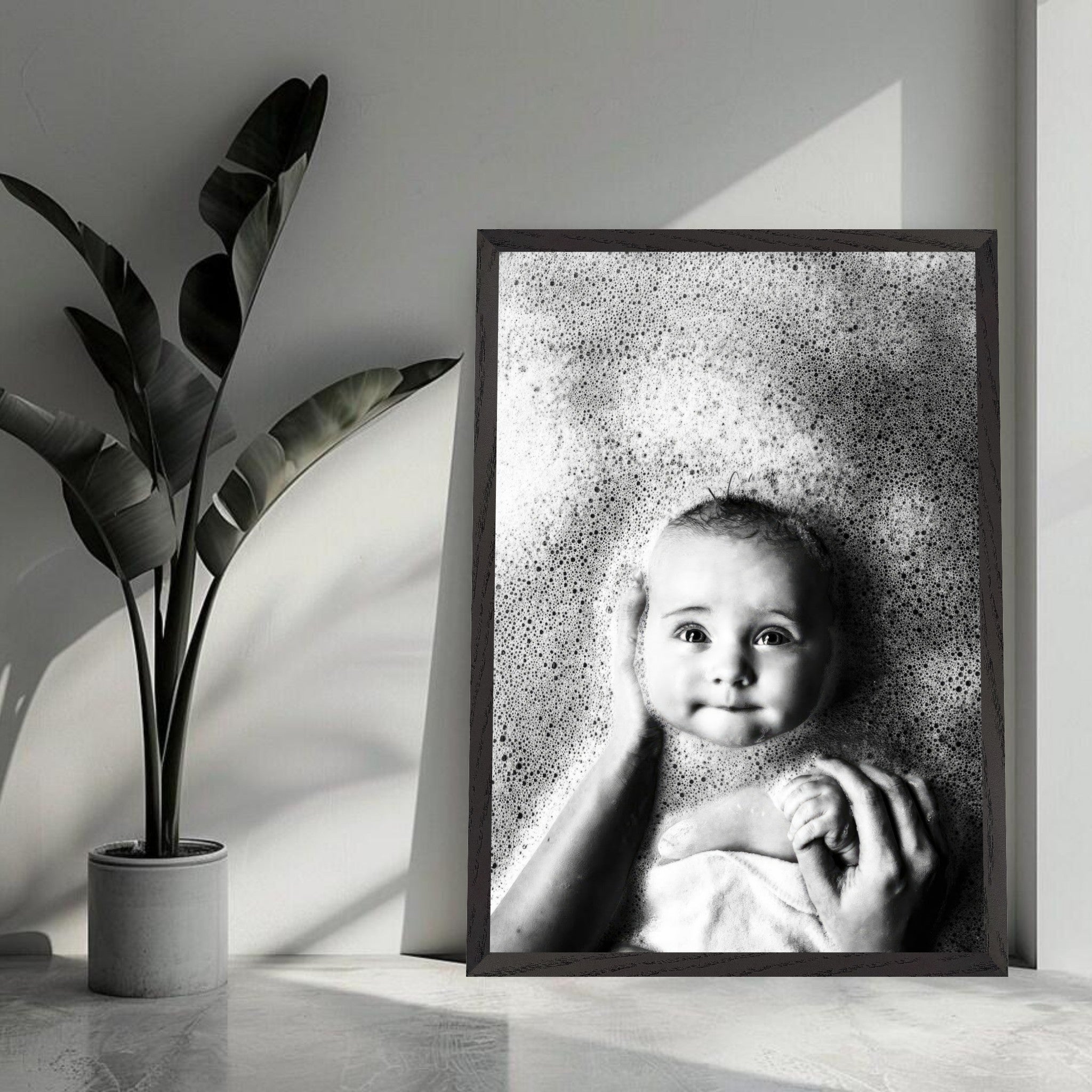 Black-and-white baby bath photography print showcasing a smiling infant surrounded by gentle bubbles.