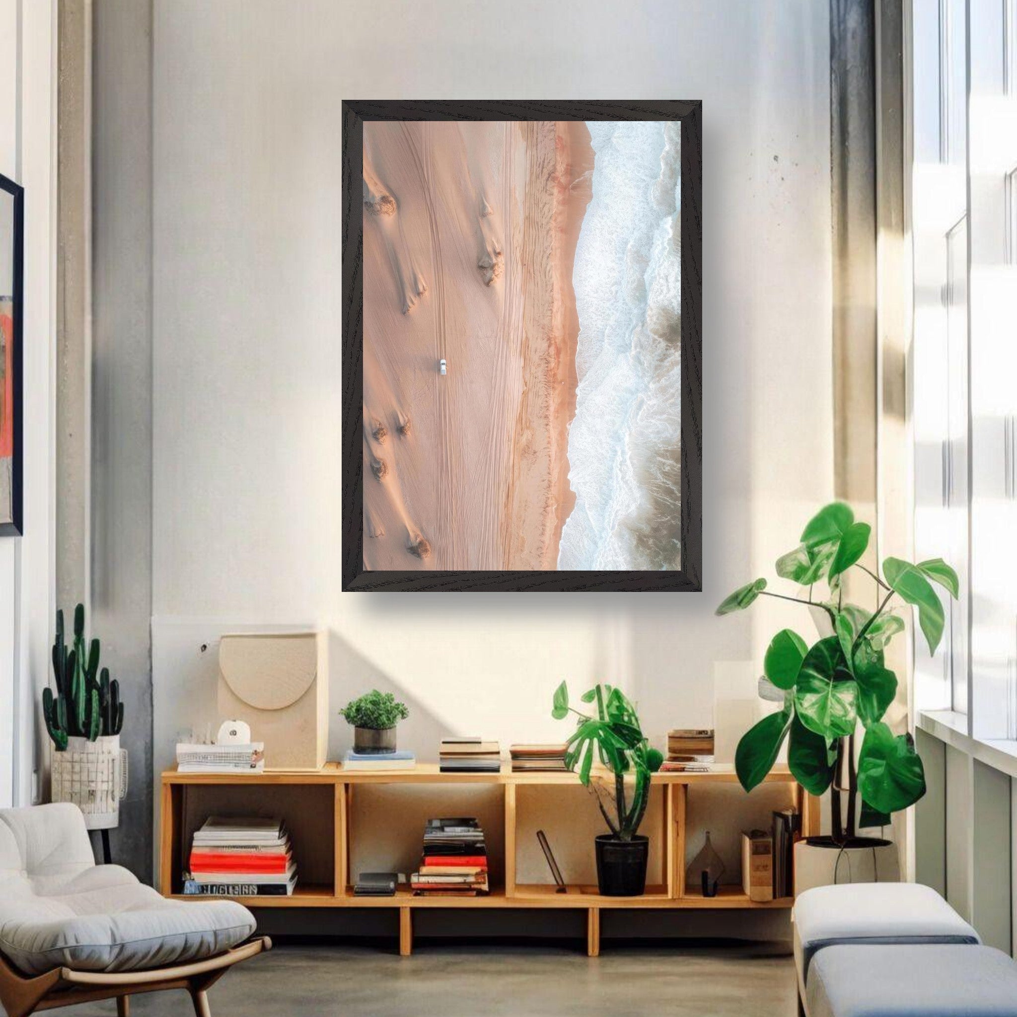 Vintage framed print of drone photography showing desert dunes and ocean waves in a modern living room.