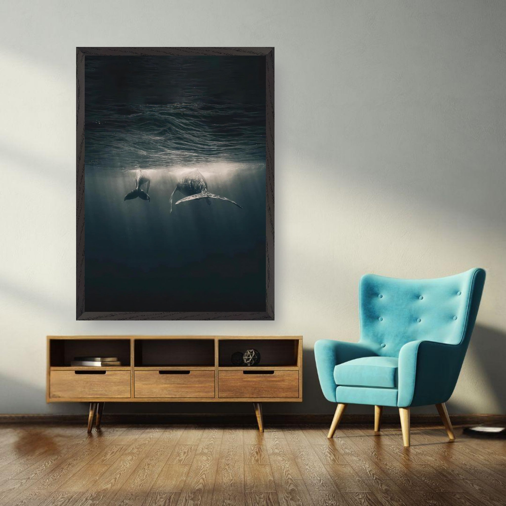 Whales swimming underwater in a fine art print, framed beautifully above a stylish teal chair.