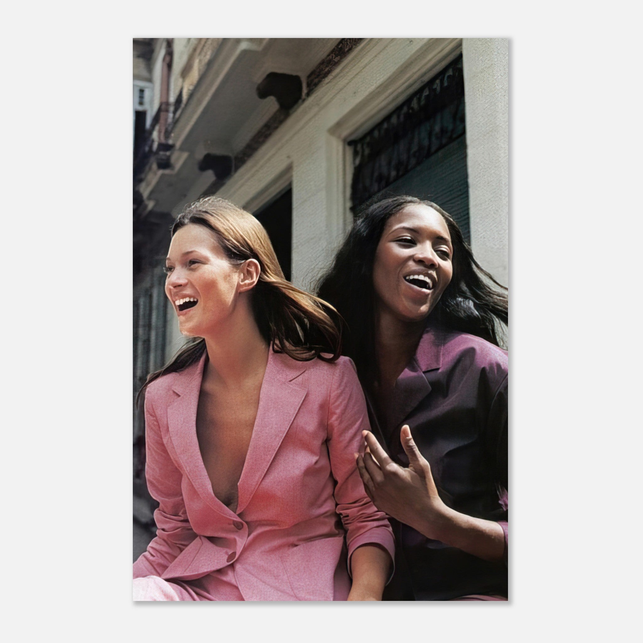 Naomi Campbell and Kate Moss laughing together in stylish suits, showcasing timeless fashion in a vibrant metal print.