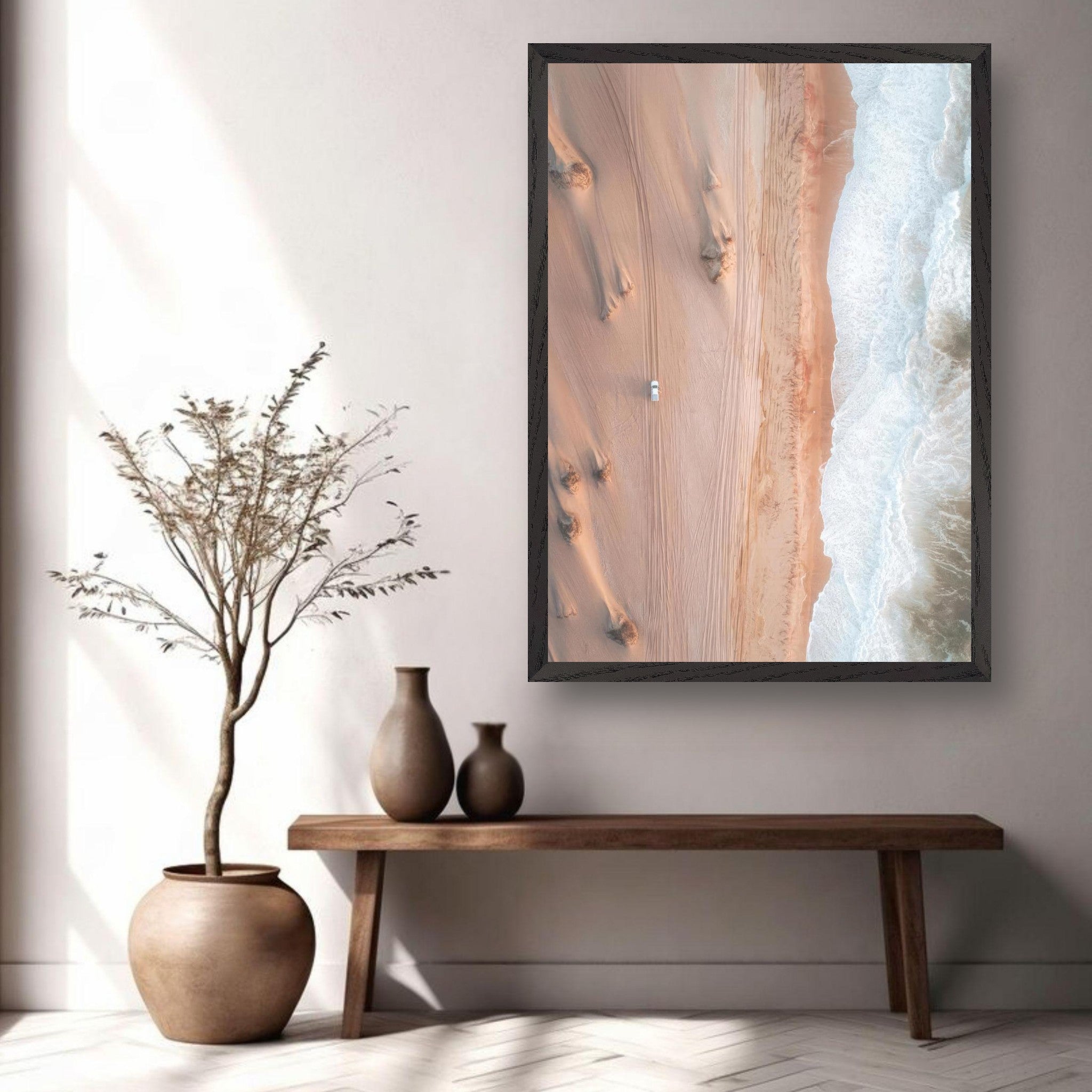 Aerial drone photography artwork of desert dunes meeting ocean waves, framed and displayed in a modern interior setting.