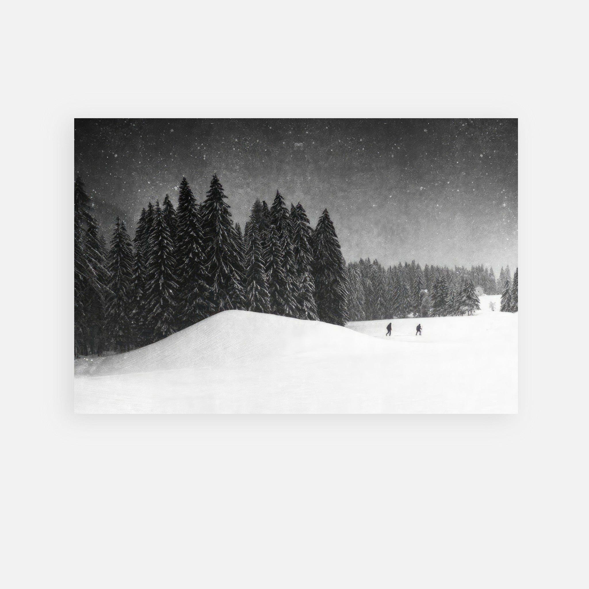 Black-and-white metal print of a snowy landscape with two figures crossing a field surrounded by tall evergreens.