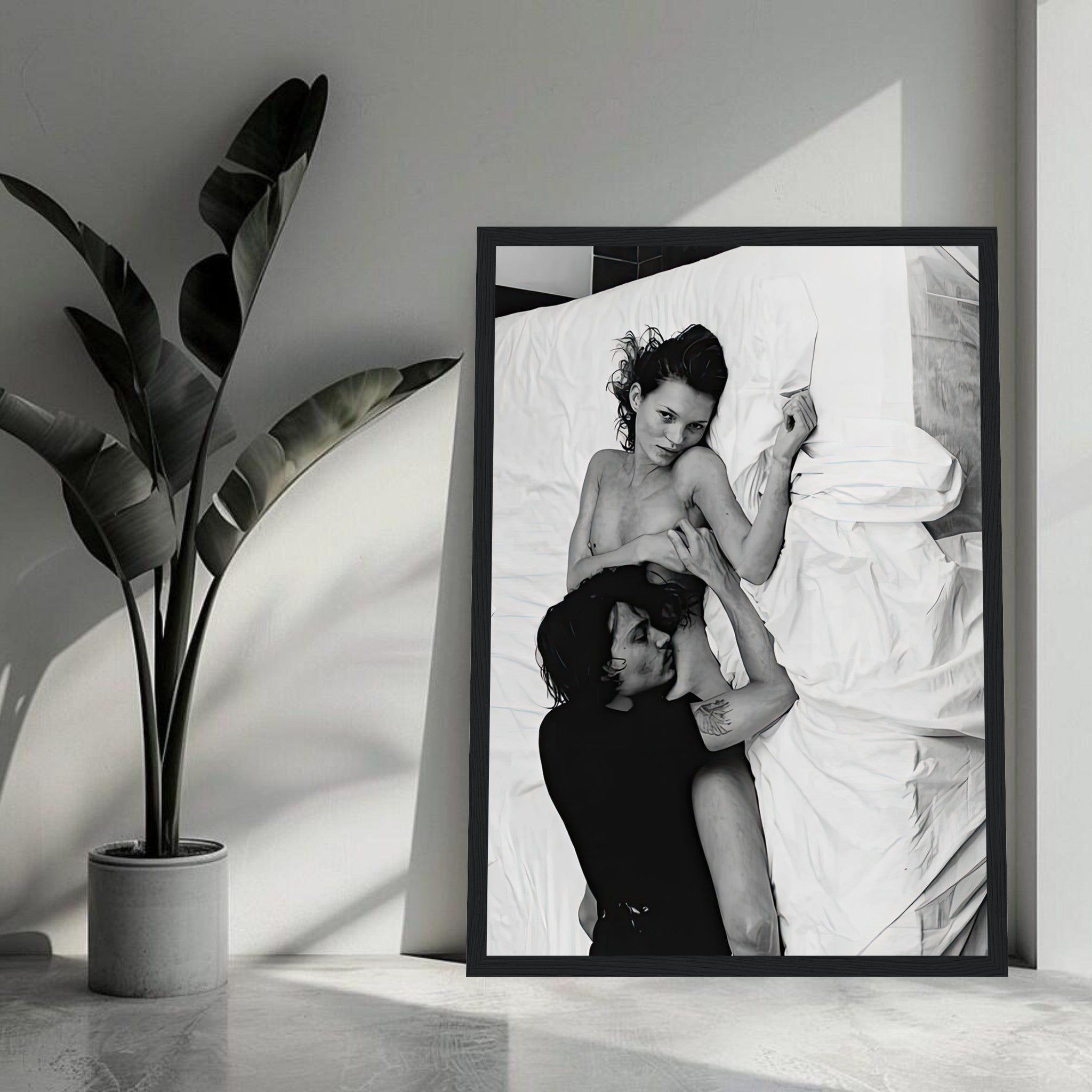 Framed black-and-white print of a couple on a bed, capturing intimacy and emotion in a chic interior setting.