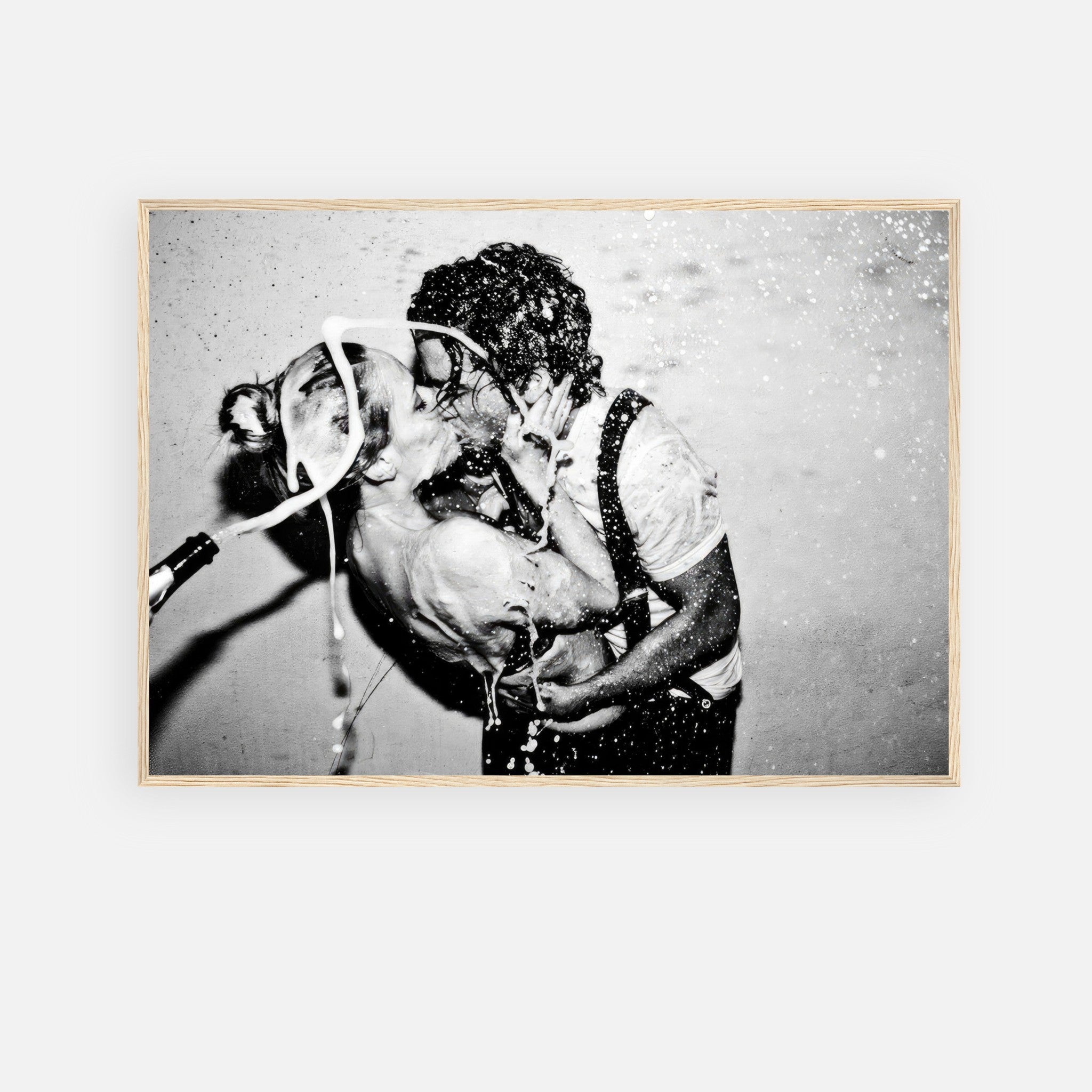 The Champagne Kiss black-and-white framed print featuring a passionate kiss and champagne explosion.