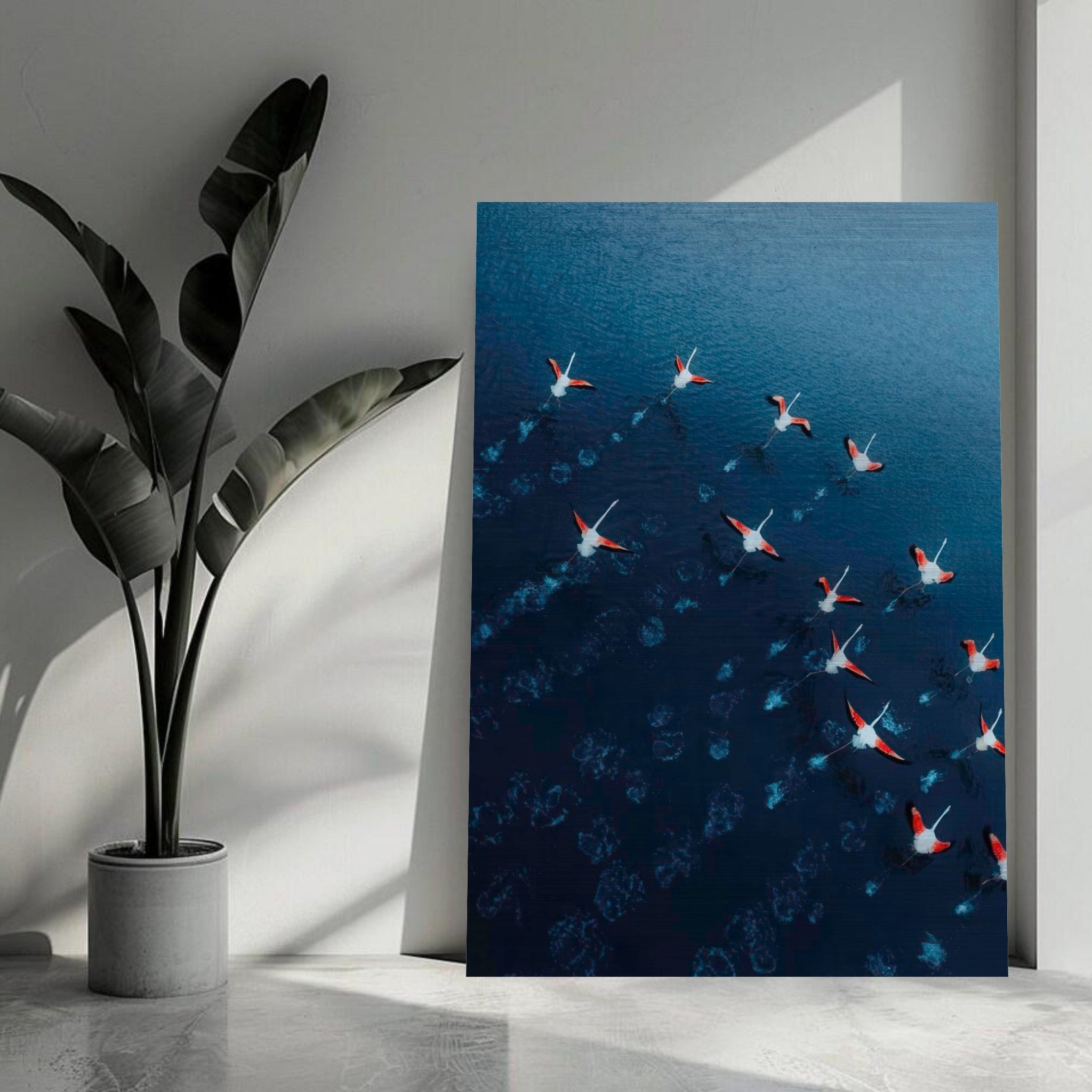 Aerial view of vibrant flamingos gliding over deep blue water in a brushed metal print.