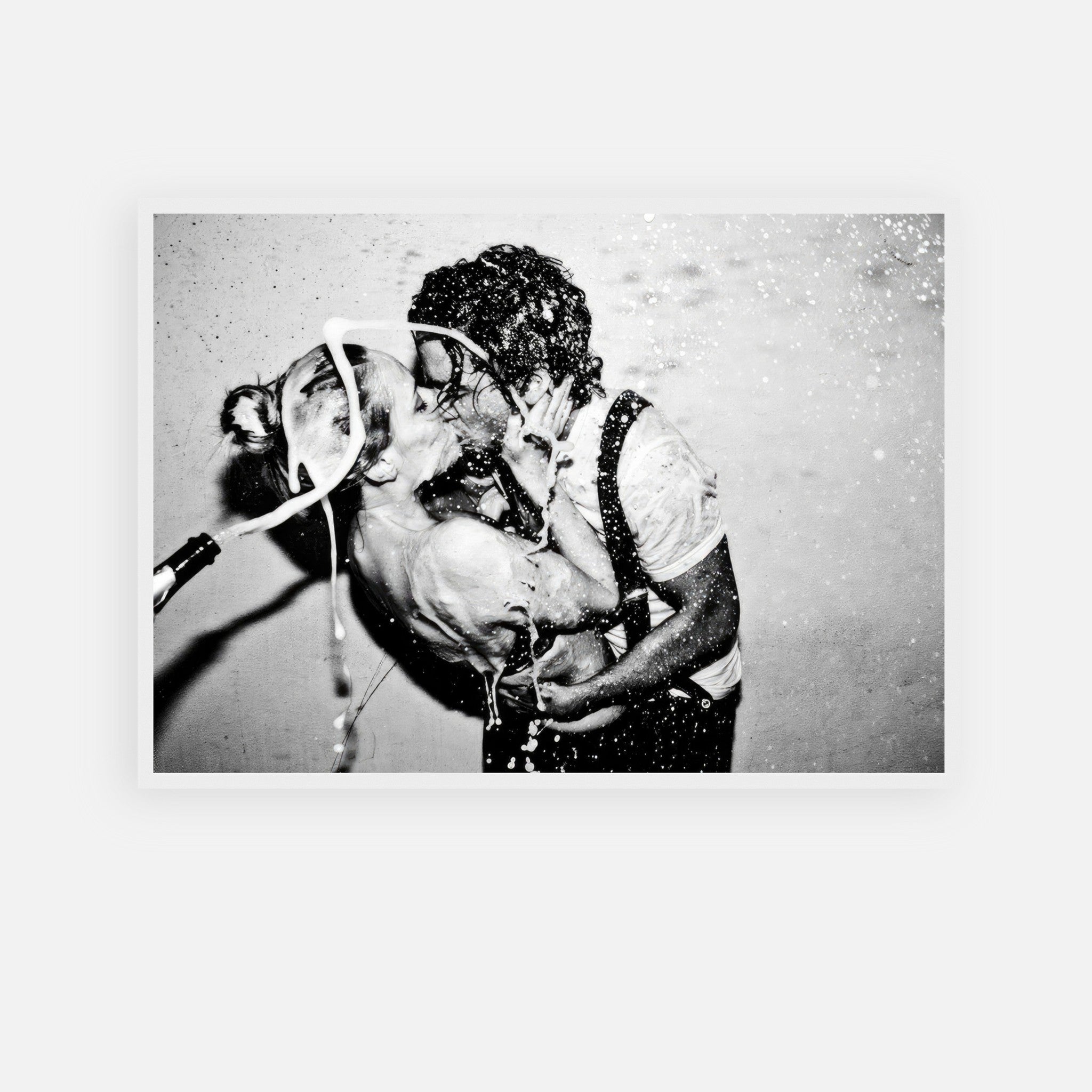 Black-and-white print of passionate kiss between couple with champagne spray, evoking glamour and rebellion.
